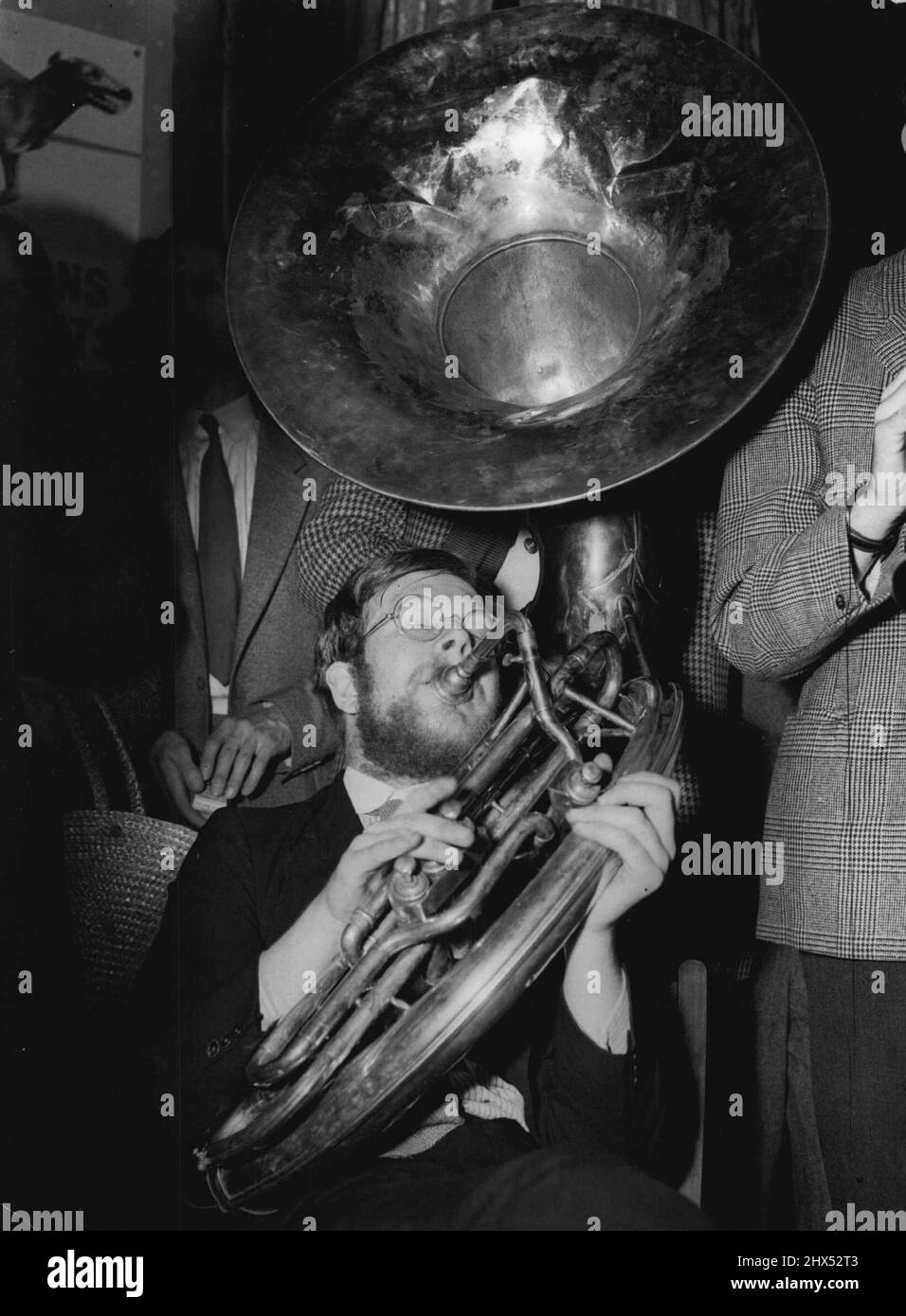 Hot For Lunch -- He Presses the middle note down, the music goes round and round - and comes out at the top as Jazz. His name is Douglas Gray, 23, and the instrument he is playing is the Sousaphone. He is a member of the Fleet-Street Jazz Club, London, which holds lunchtime meeting every week in an upstairs room of a pub. Everything is served hot. September 16, 1954. Stock Photo