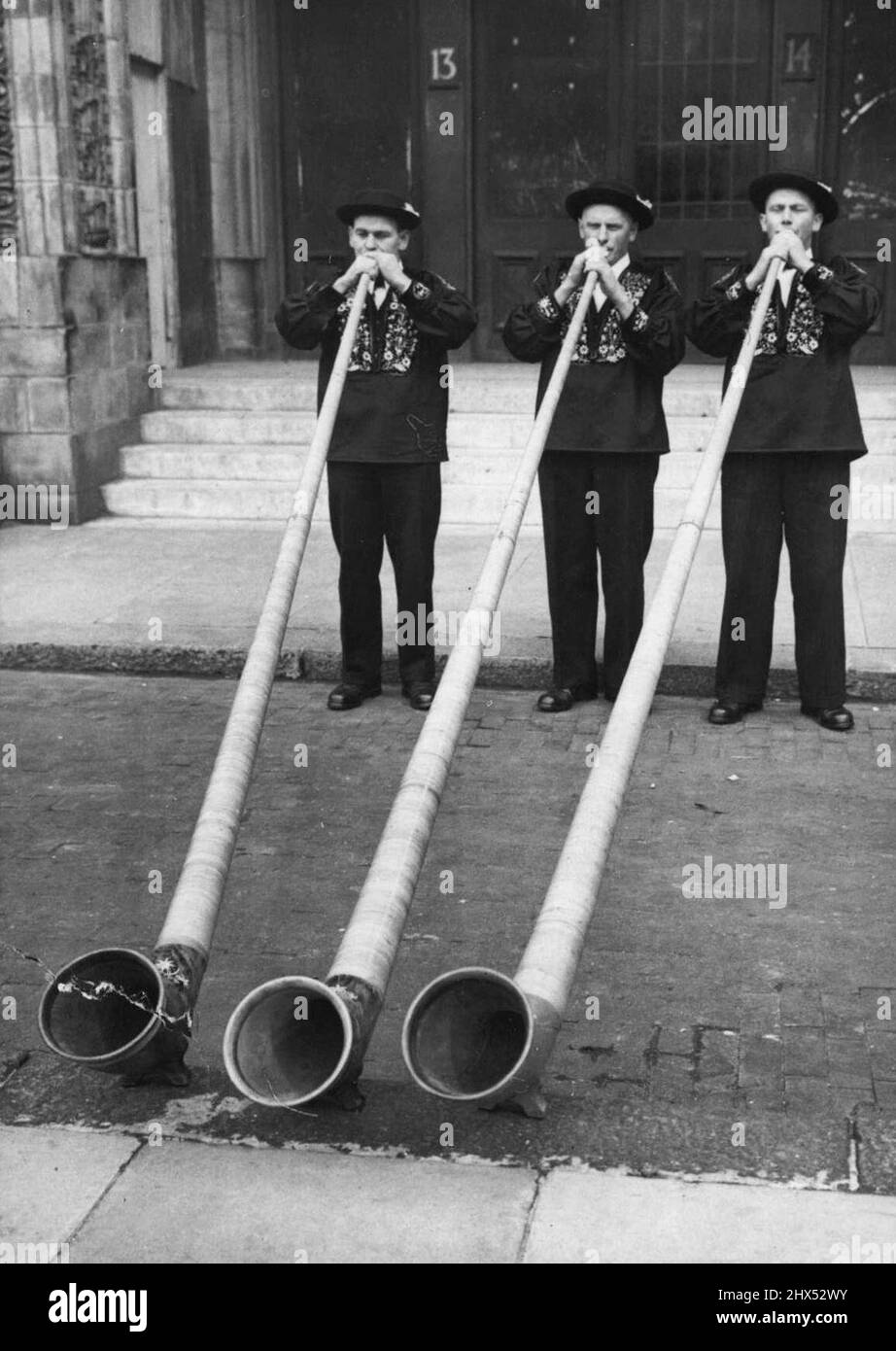 Blowing Their Own Trumpets! -- Swiss mountaineers demonstrating their skill on the 12 feet long wooden alp-horns. The men are among the 145 Swiss men and women taking part in the Swiss Folklore Festival at the Royal Albert Hall, London. Each participant is paying his or her own expenses as a tribute to the wartime work of the Royal Air Force. May 25, 1948. (Photo by Sport & General Press Agency, Limited). Stock Photo