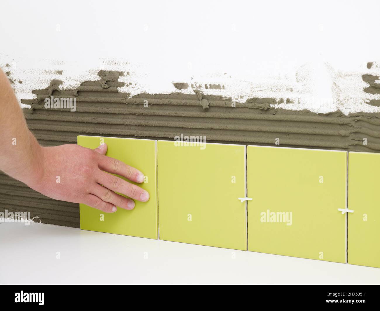 Tiling a bathroom, fixing a row of whole tiles in place, starting from