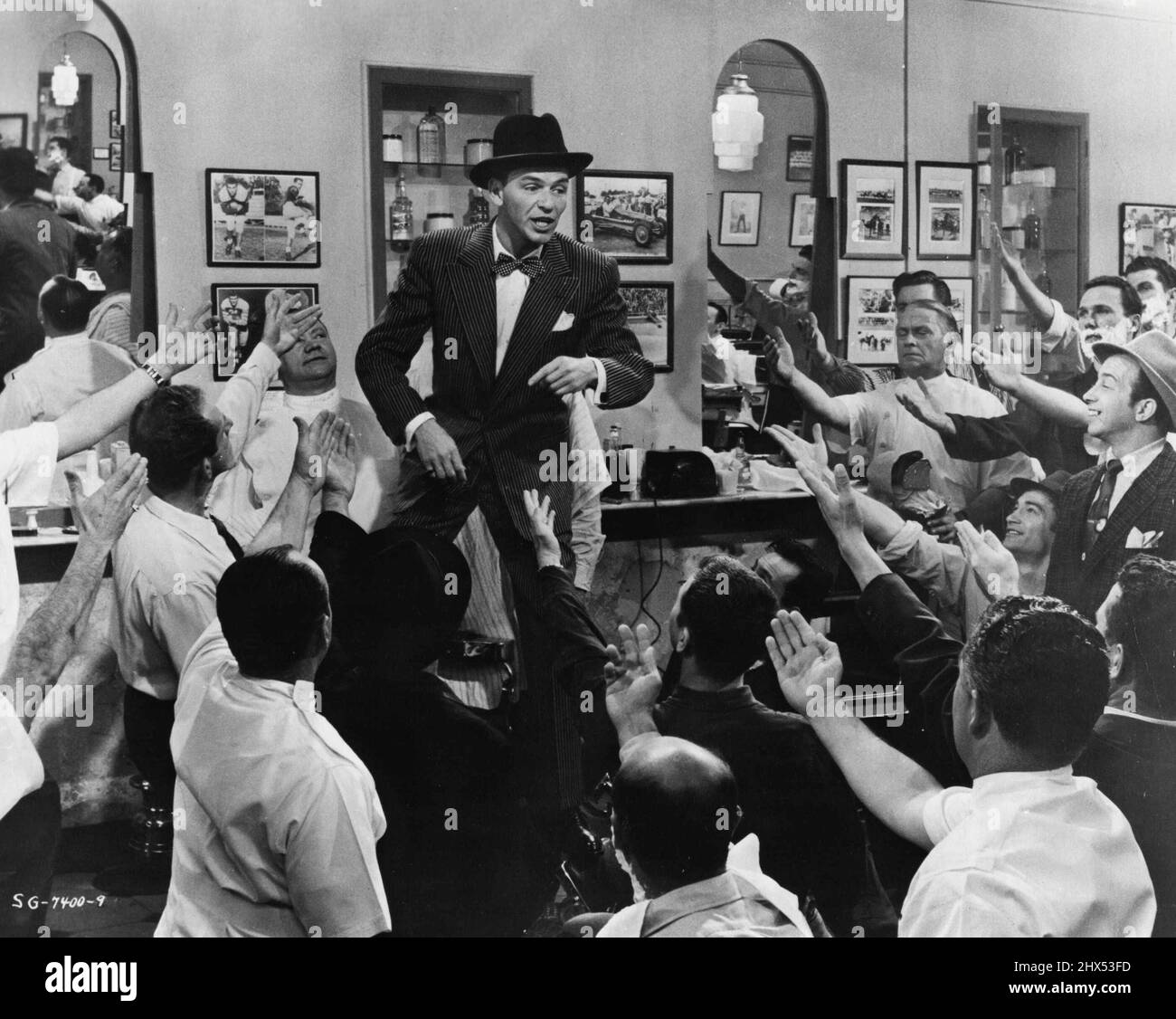 Tonsorial Tribute Nathan Detroit (Frank Sinatra) as proprietor of the 'oldest established permanent floating crap game,' receives a tribute from the barber shop patrons in scene from the Samuel Goldwyn production of 'Guys and Dolls' The lavish film musical, being released by MGM, stars Marlon Brando, Jean Simmons, Sinatra and Vivian Blaine. October 31, 1955. Stock Photo