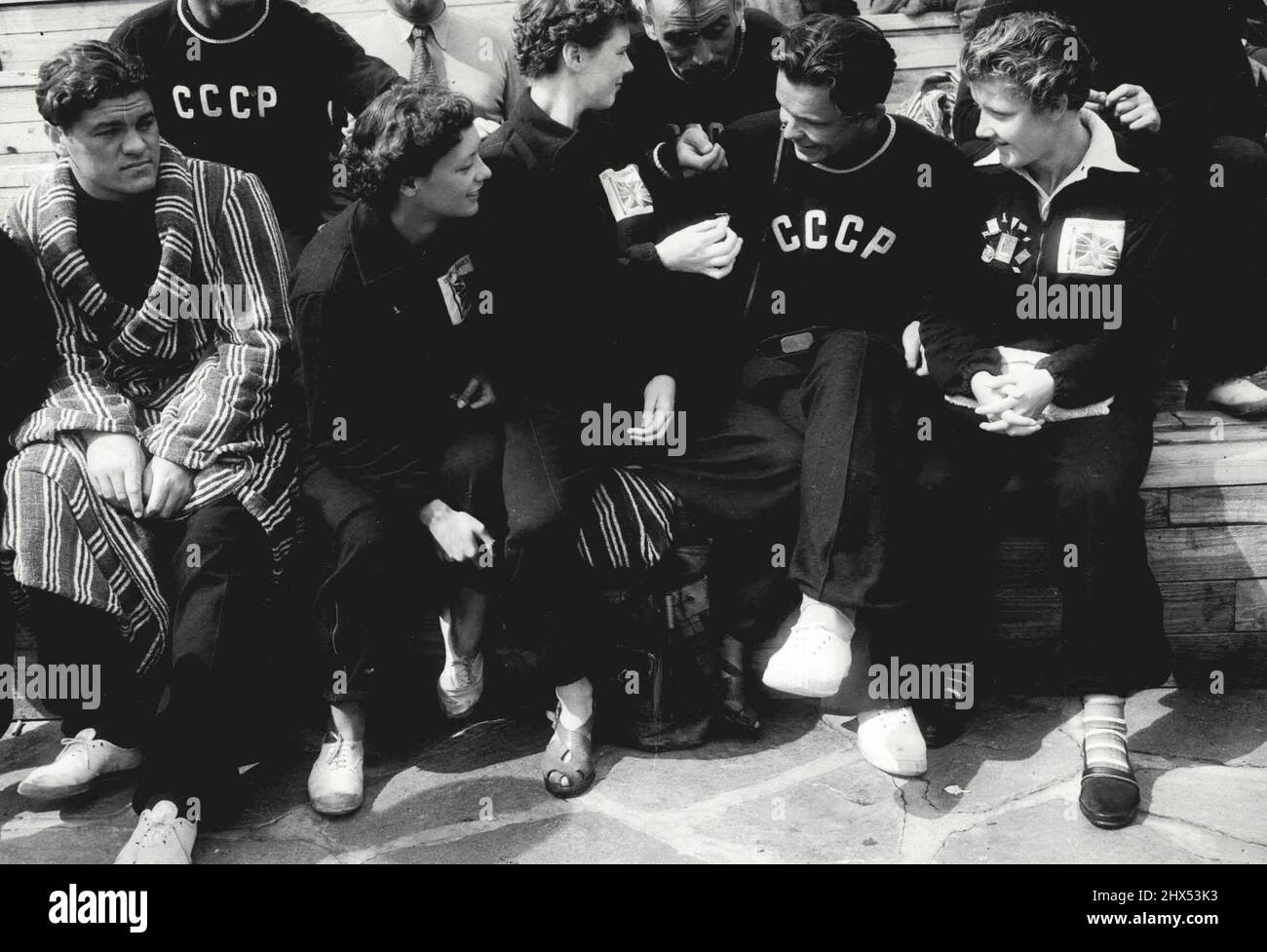 Halsinki Badge-Swappers - Badge-Swapping at the Olympic pool. Left to right: 15-year-old Pauline Musgrove, of York, youngest member of the British team, Jean Wrigley, of Oldham, Vadim Bubok, of the Russian polo team, Jean Botham, of Manchester, and other Russian polo players looking on. Latest craze among competitors at the Olympic games in Helsinki is Badge-swapping. Enthusiastic devotees of the Fad are the Russian Athletes, who now have many foreign Badges in their collections. July 23, 1952. (Photo by Paul Popper). Stock Photo