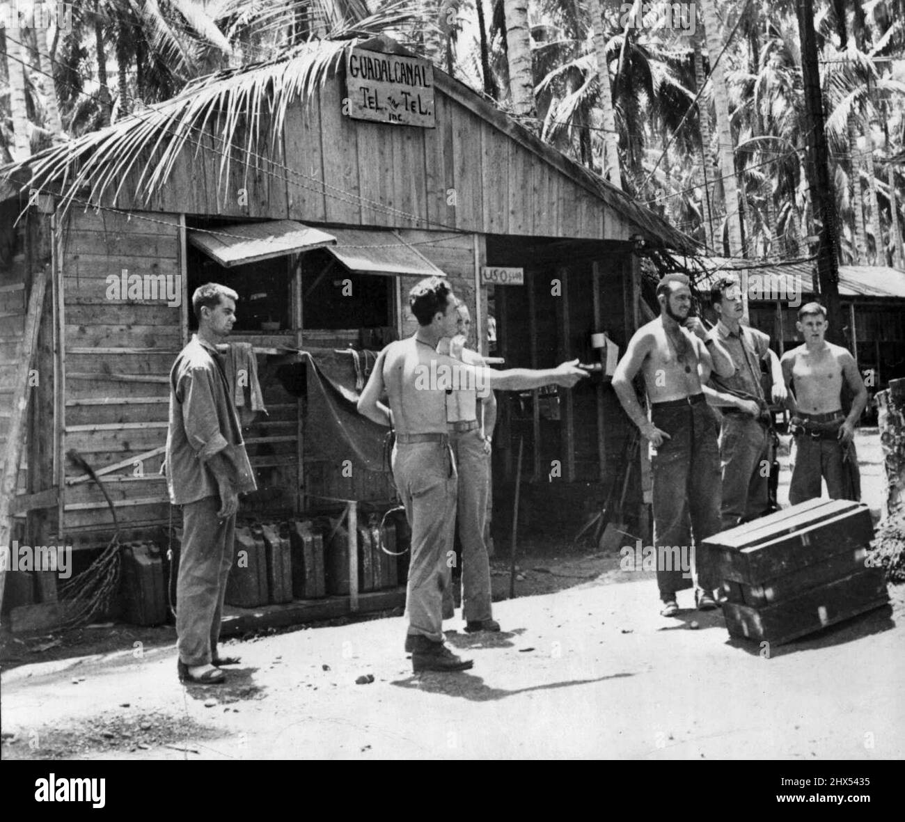 Marines' Communications Center At Base On Guadalcanal Island -- In this picture from the fighting front on Guadalcanal a group U.S. Marines are seen outside the telephone building, communications Headquarters for a unit of the American forces on the island. November 23, 1942. Stock Photo