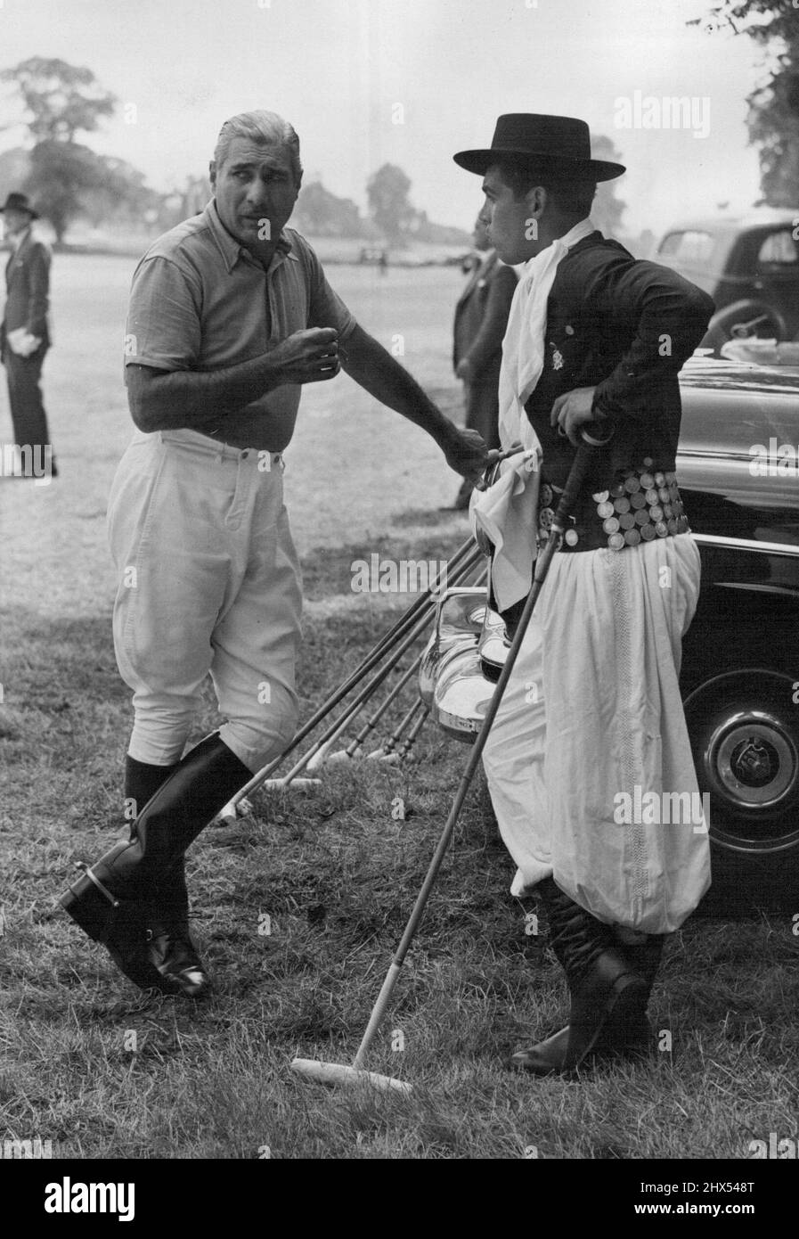 Hurlingham Beats Argentine team to win ***** Festival Cup - One of the Argentine players chats with an attendant holding the sticks, and dressed in colorful gaucho costume. The Hurlingham Polo Team yesterday beat La Espadana from the Argentine for the second time to win the Festival Cup at the Roehampton Polo Ground. Among the spectators were Princess Elizabeth who presented the trophy and Princess Margaret. July 26, 1951. (Photo by Fox Photos). Stock Photo