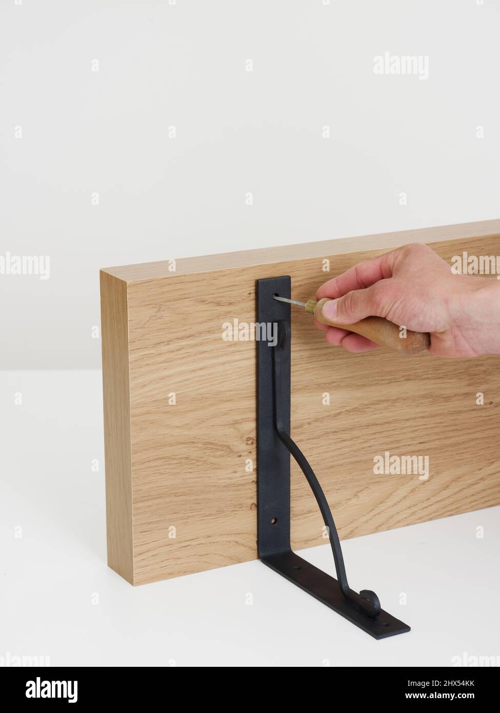 Fitting wall shelves, attaching the brackets, using a bradawl to make