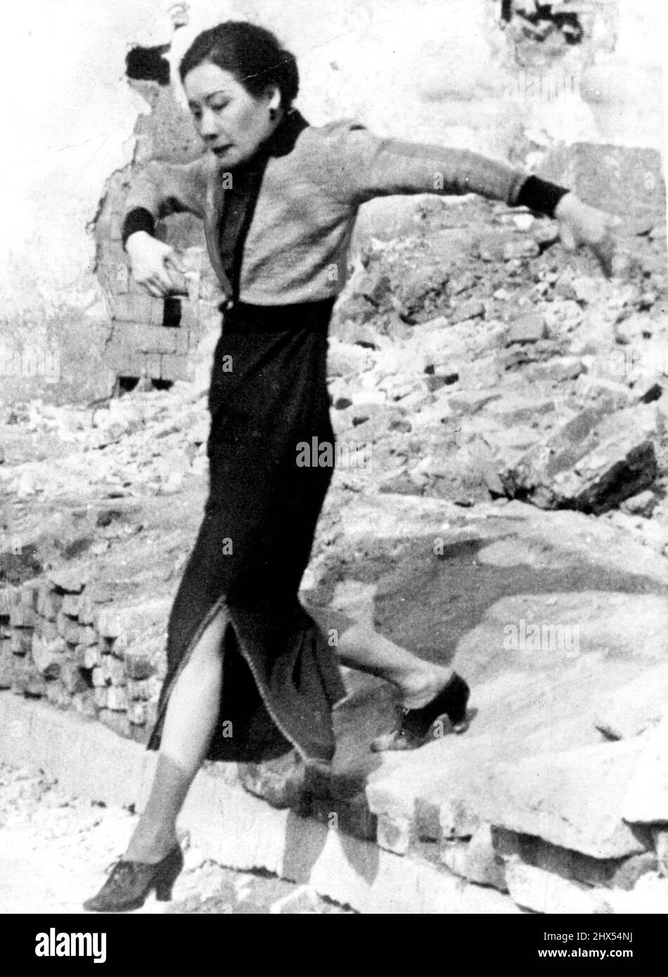 Madame Chiang Kai-Shek Inspects Japanese Bomb Damage In Chungking -- Madame Chiang Kai-Shek, the wife of China's famous Generalissimo, is seen here stepping over the Debris of Houses bombed by Japanese aeroplanes in Chungking, the present provisional capital of China -- A picture just received in London today, April 29, which brings home to us the fact that, in spite of Europe's present war-like troubles tending to overshadow our thoughts at present war, with all its attendant bombing ***** is still going on in the far east. May 21, 1940. (Photo by Associated Press Photo). Stock Photo