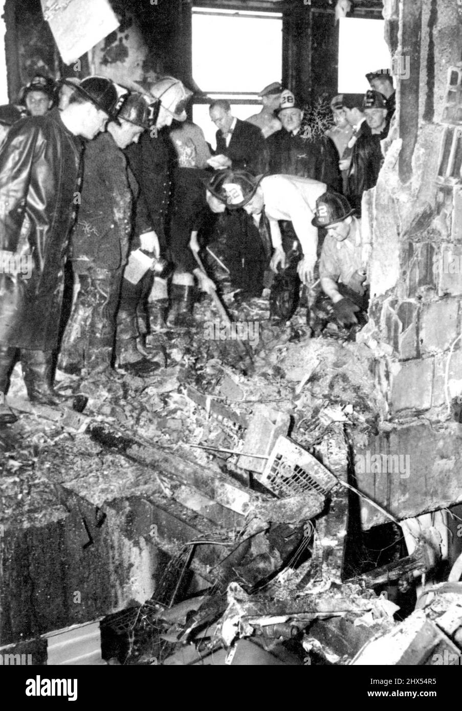 Search For Bodies Of Crash Victims -- Firemen dig through wreckage of the plane that crashed into the upper part of the Empire State Building in New York, July 28th, searching for bodies of victims of the crash. This scene is on the 79th floor, looking through the elevator shaft into an office. Hote at upper left was made by the plane. July 28, 1945. (Photo by Associated Press Photo). Stock Photo