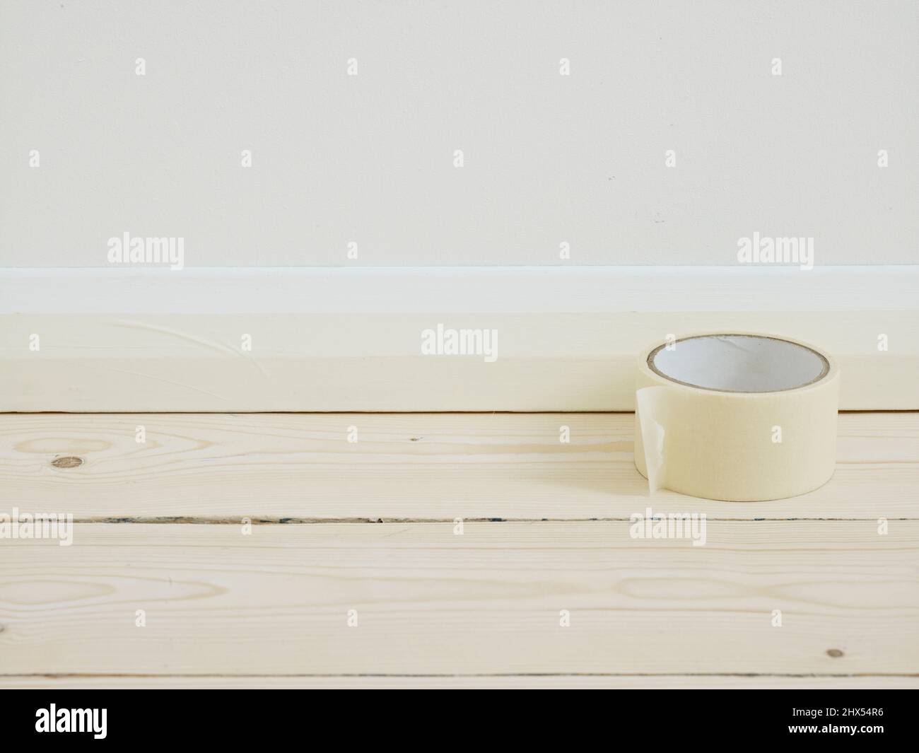 Staining a wooden floor, fixing masking tape around the base of the