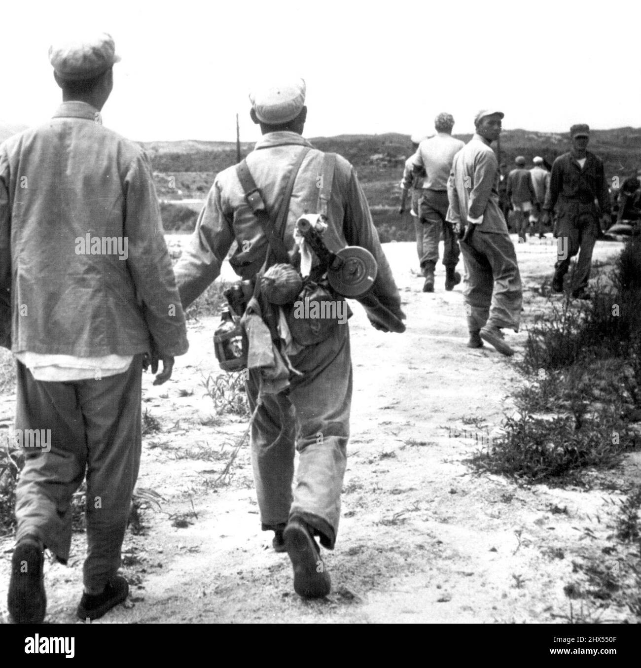 Loaded Soldier -- Two Chinese communist soldiers, one loaded with gear including a sub-machine gun, walk away from a UN photographer whose convoy to Kaesong was halted Friday by high waters. Allied engineers have been working to repair flood damage so cease-fire convoy can get through tomorrow when the Communists are expected to give their answer to the Armistice agenda. July 24, 1951. (Photo by AP Wirephoto). Stock Photo