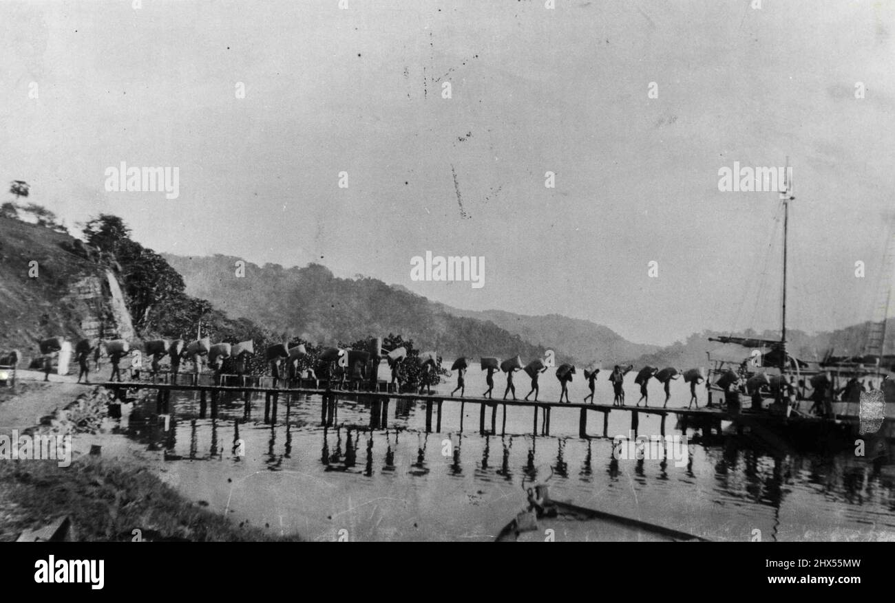 Any handy vessel was used at Tulagi to lighter copra to big ships lying offshore. Natives manhandled it aboard. November 30, 1955. Stock Photo