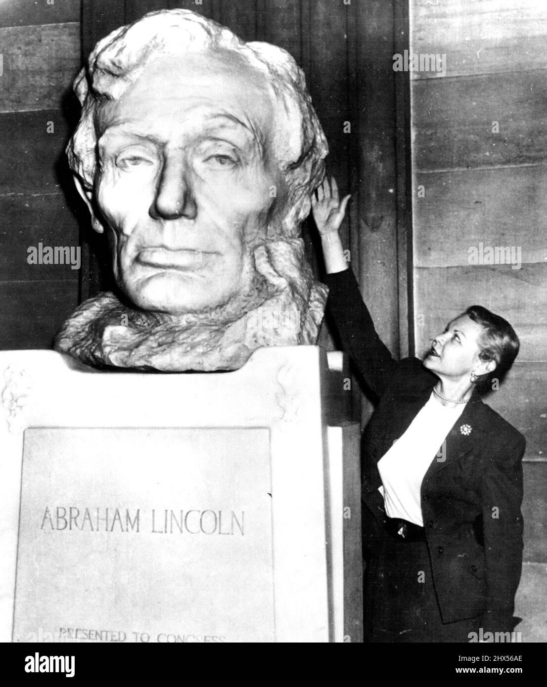The One Ear Was No Accident -- Mariann Remke of East St. Louis, Ill., points out the puzzling feature of this famous marble head of Abraham Lincoln -- the missing left ear. Sightseers have wondered about it for the 46 years the work has been on display in the capitol rotunda, but Gutzon Borglum, the sculptor, wrote a committee of congress in 1908 that he planned it that way to emphasize the fact that 'Lincoln's face was so much more developed on the right side.' Robert Lincoln called the head. The most extraordinarily good portrait of my father I have ever seen. Miss Remke is secretary to Rep, Stock Photo