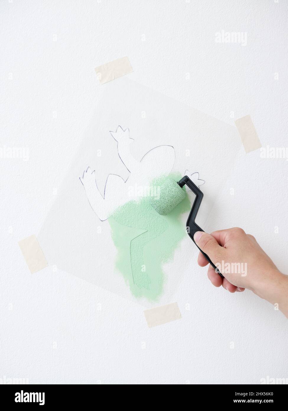 Using a sponge roller to apply paint over the stencil onto the wall