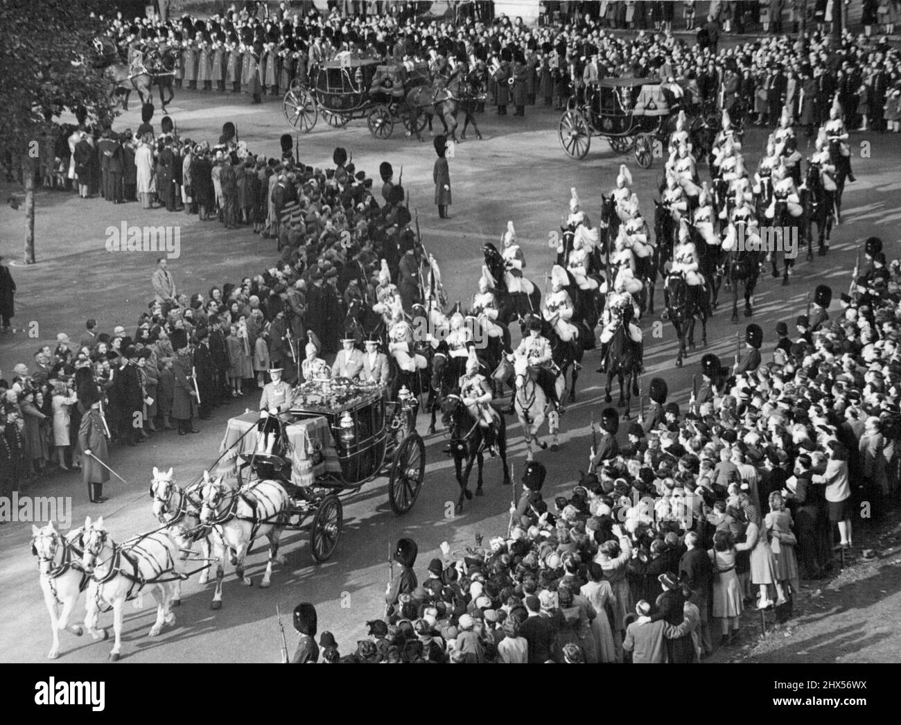 King and Queen on Way to Open Parliament: The black and gold Irish State coach drawn by four Windsor Greys and Bearing their Majesties, King George VI and Queen Elizabeth , turns into horse Guards Parade on way from Buckingham Palace to the Houses of Parliament Westminster, London, this morning October 26. The household Cavalry follow with four State Landaus carrying officers of the Royal Household and members of the Royal Suite bringing up the rear.The King was visiting Parliament this morning for the first state opening with full ceremony since 1938. The Imperial State grown and Parliamentar Stock Photo