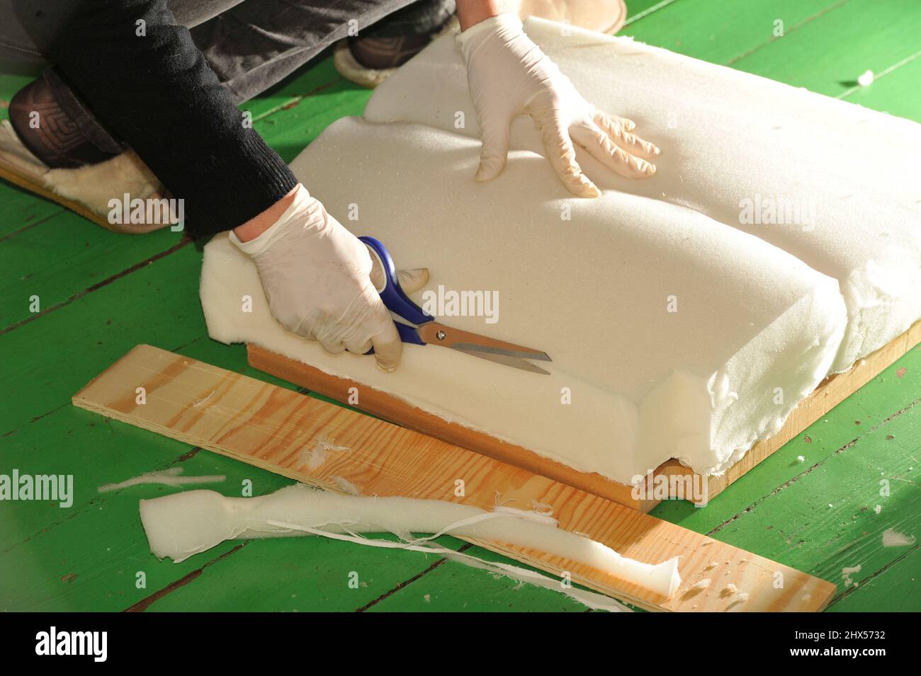 Stuhl mit Leder neu beziehen .Woman upholstering a kitchen stool Stock