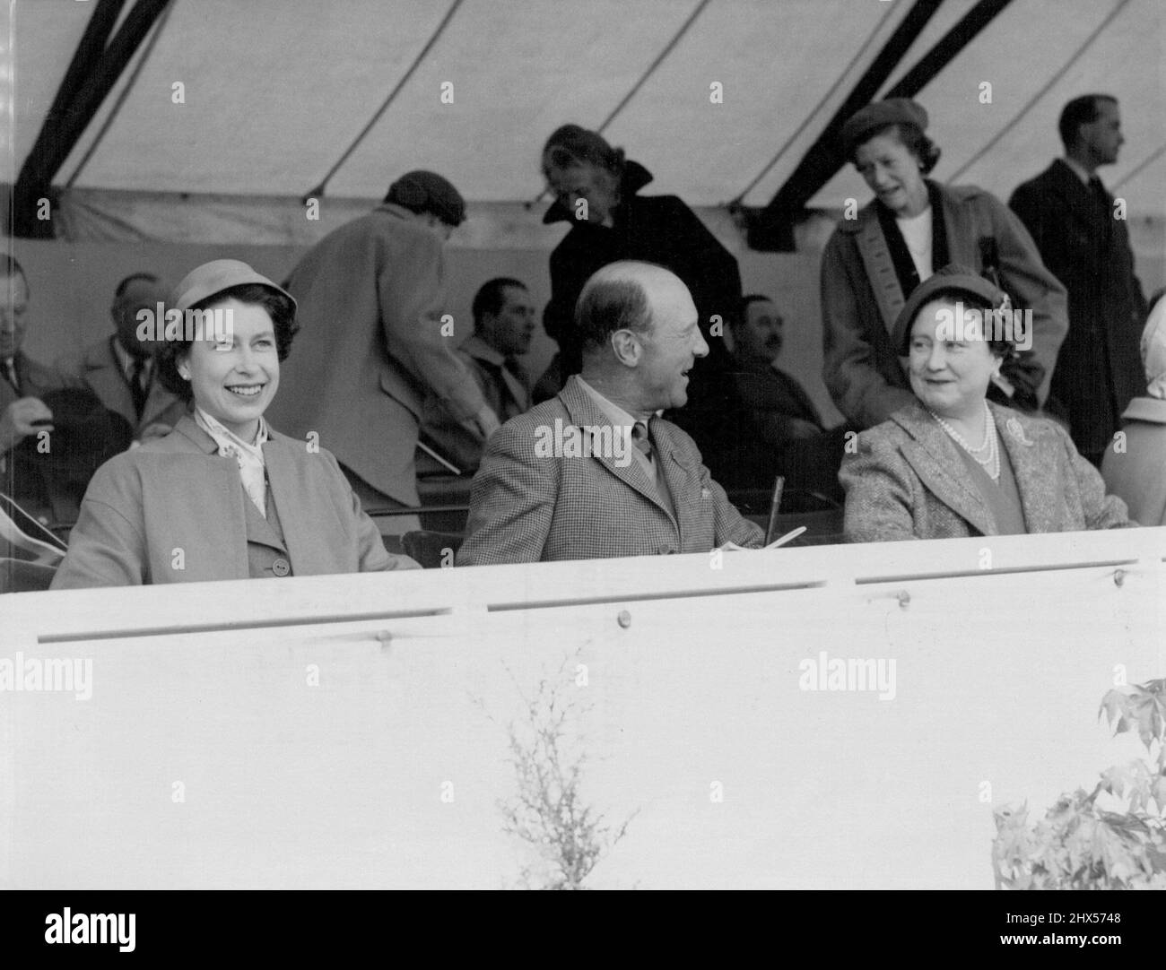 Horse Trails Delight The Queen - The Queen in new style hat to match her orange coat, smiles as her mother, Queen Elizabeth, the Queen Mother, talks with the Duke of Beaufort, master of the horse, at the dressage tests, held on the opening day of the European horse trials in Windsor great park to-day (Wednesday). May 18, 1955. (Photo by Reuter Photo). Stock Photo