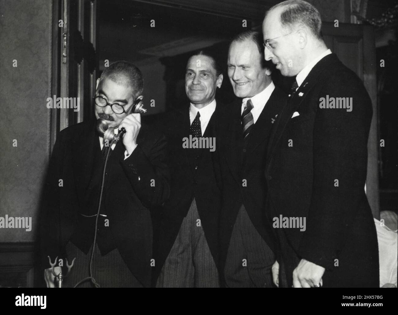 Japan, Germany And Italy Form Mutual Assistance Pact - Foreign minister Yosuke Matsuoka in a telephone conversation wilt Berlin soon after the signing of the German-Italian-Japanese mutual assistance pact there at Chancellor Hitler's chancellery. He is exchanging salutations with German Foreign Minister Joachim Von Ribbentrop and Italian Foreign Minister Galeazzo Ciano. Shown beside him are, left to right: Italian Ambassador Mario Indelli, German Ambassador Eugen Ott, and German minister-at-large Stahmer, who played an important role in the conclusion of the tripartite alliance. October 28, 19 Stock Photo
