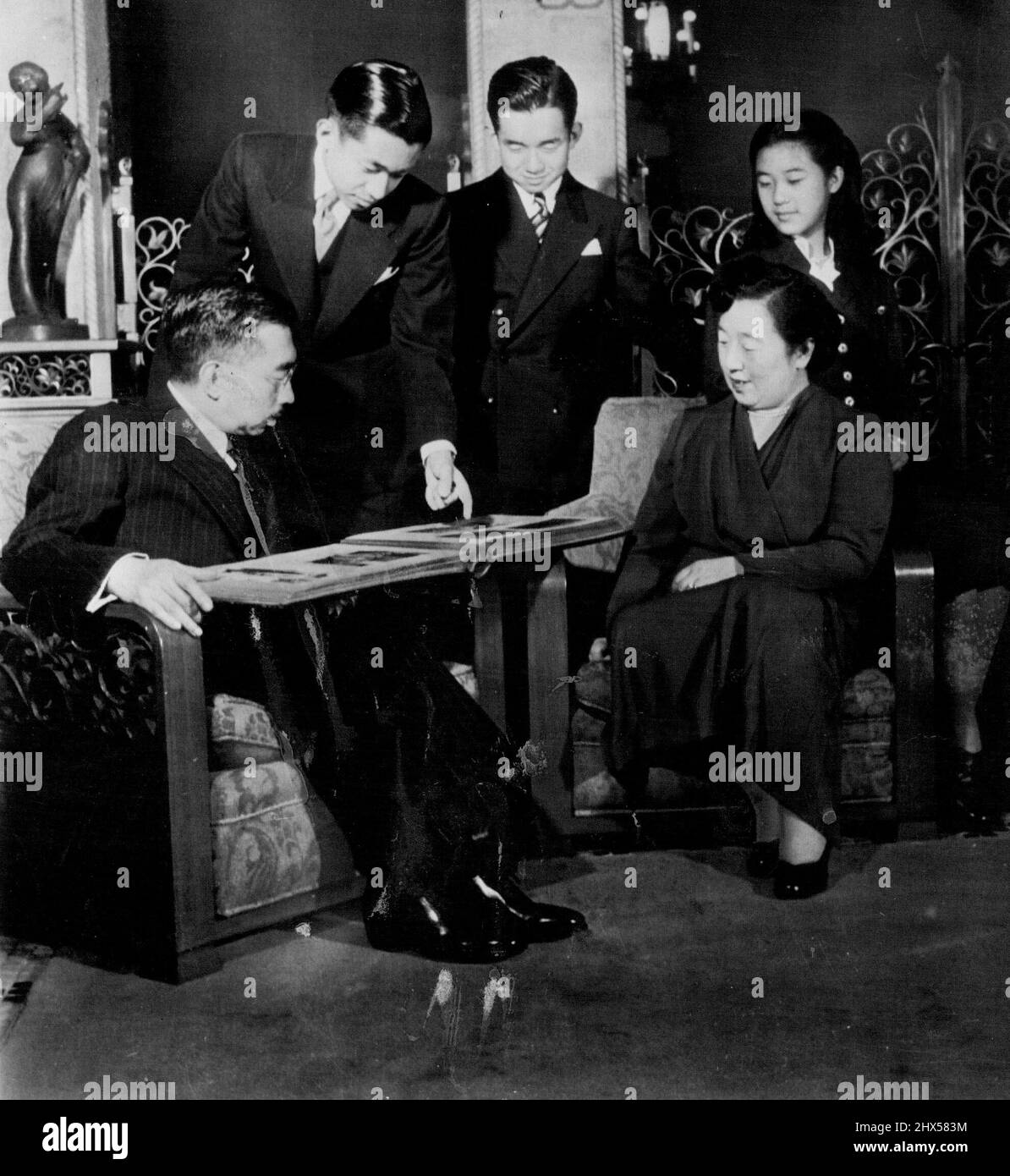 Japan's Imperial Family -- Japanese Emperor Hirohito and members of his family look through a photo album at the Imperial palace in Tokyo in this picture released this week by the Imperial household. Left to right: the emperor; his sons, Crown Prince Akihito and Prince Masahito; Empress Nagako, and daughter Princess Takako. December 27, 1952. (Photo by AP Wirephoto). Stock Photo