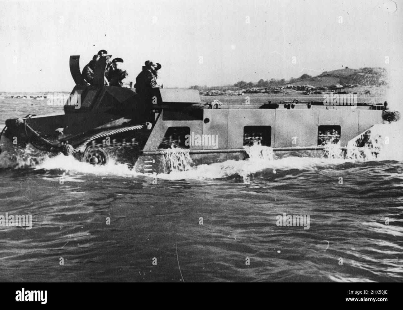 The Neptune Amphibious Tank -- 'Neptune' putting out to sea. This British tracked amphibious vehicle is a ship-to-shore load carrier capable of self-propulsion in any sea, able to land on a beach through heavy surf, and to move across country. 'Neptune' can take a pay load of approx; four tons and has a large unobstructed hold, which makes it particularly suited for the carriage of a wide variety of equipment, including the 17-pounder anti-tank and 25 pounder filed guns, vehicles, casulaties, and stores. 'Neptune' is equipped with navigation lights in addition to normal road lamps, a wireless Stock Photo