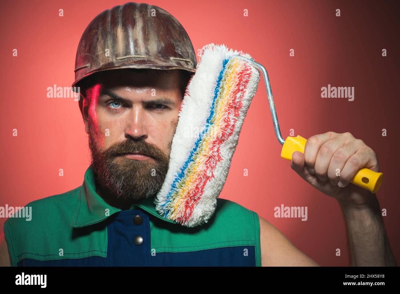 Bearded painter man in hard hat with paint roller. Male Construction