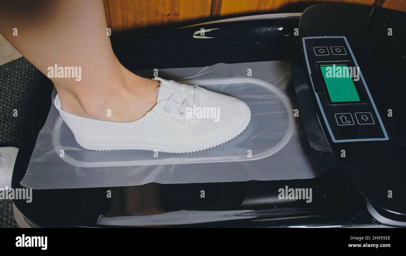 automatic thermal shrinkable shoe cover laminating machine close up dispenser in hospital hall machine automatically applies shoe covers to the patient shoes in operation sterility hygiene 2HX592E