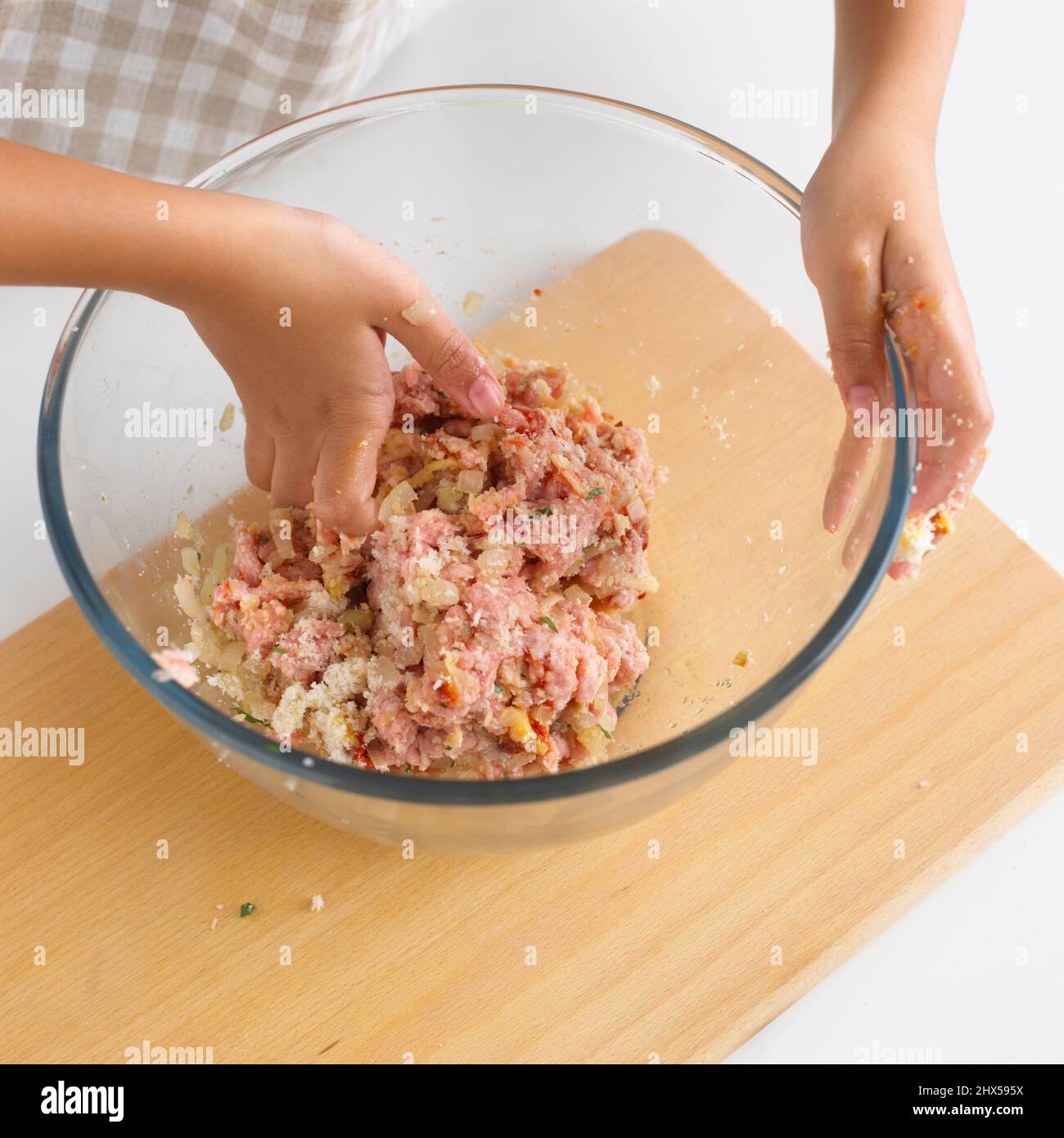 https://c8.alamy.com/comp/2HX595X/girl-mixing-raw-meat-ball-ingredients-in-large-glass-bowl-using-hands-close-up-2HX595X.jpg