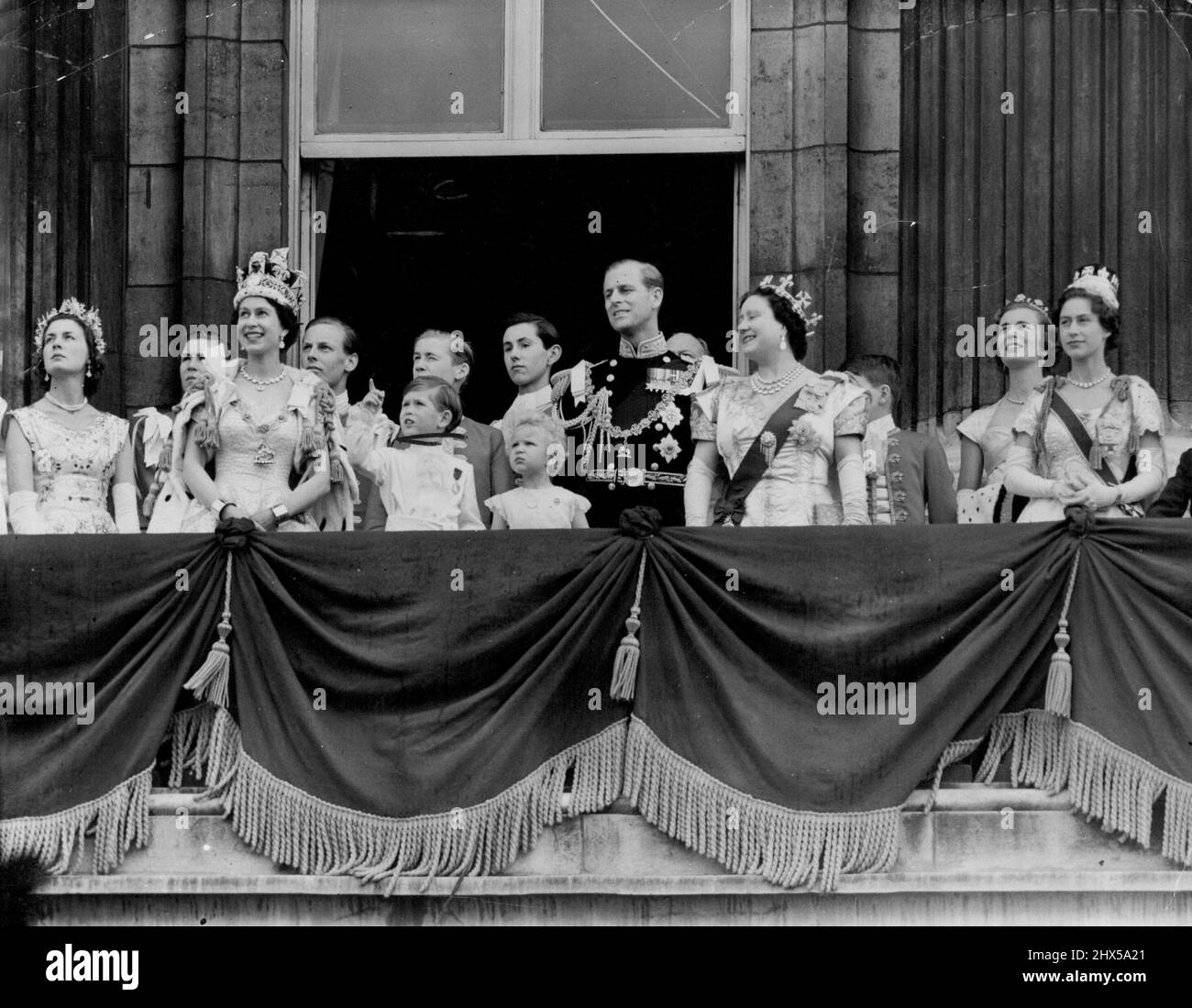 Queen Takes R.A.F. Salute - With a Pointer From Princes Charles -- Beside the smiling Queen wearing the Imperial State Crown Prince Charles points skyward from the balcony of Buckingham Palace 168 jet fighters fly over in the *****air force salute to her *****. January 01, 1953. Stock Photo