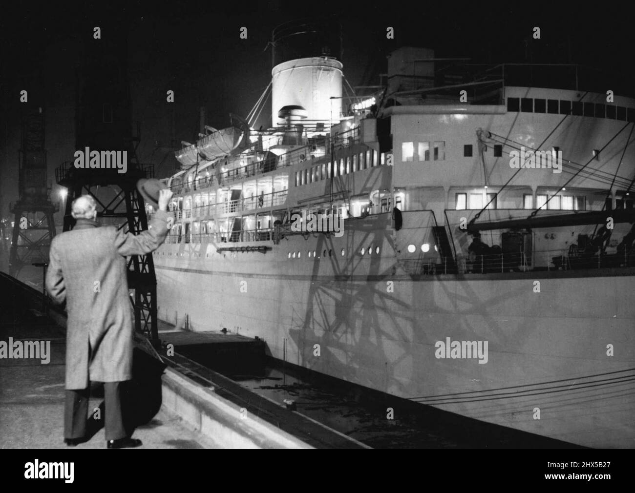 The 'Gothic' Sails for Jamaica -- An unidentified person waves from the quay side as the Royal tour ship 'Gothic' moves away from King George V Dock, to slip down the River Thames on tonight's tide, November 10th. For two hours in the afternoon, Mr. Basil Sanderson, chairman of the Shaw Savill Line, inspected her. Finally he agreed she was ready for the tour. The liner was on her way to Jamaica, where the Queen and the Duke of Edinburgh will join her November 27th. November 11, 1953. (Photo by Associated Press Photo). Stock Photo