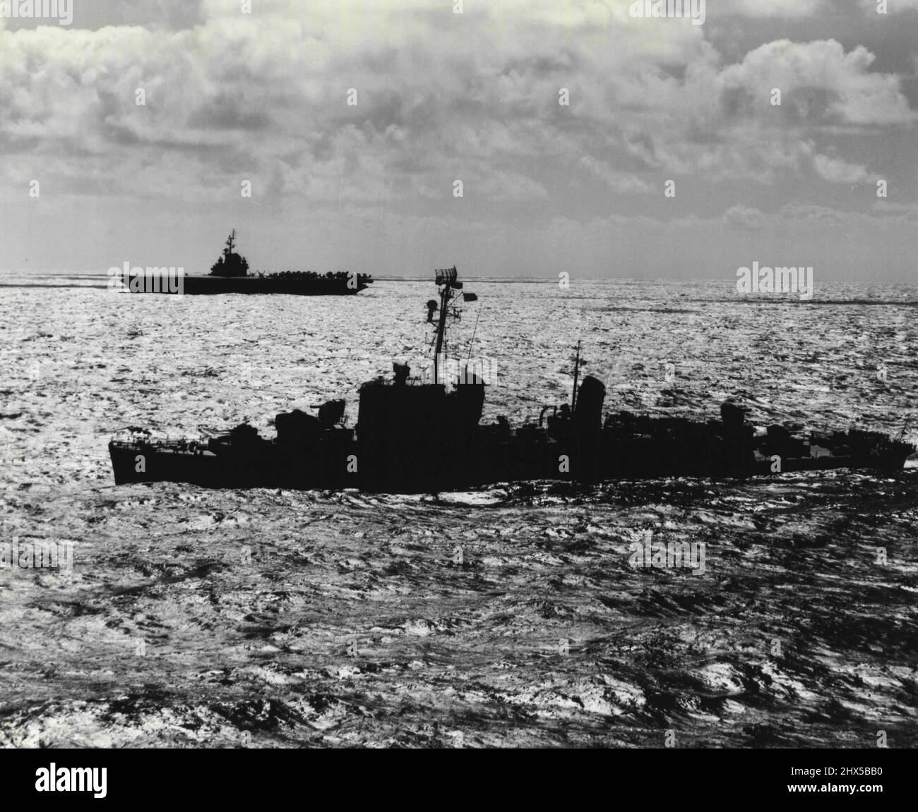 Japan Sea Silhouette - The destroyer USS Carpenter escorts the carrier USS Essex, flagship of East Carrier Task Force 77 as they steam through Korean Coastal waters to strike at Communist targets in North Korea. September 18, 1951. (Photo by Official U.S. Navy Photograph) Stock Photo