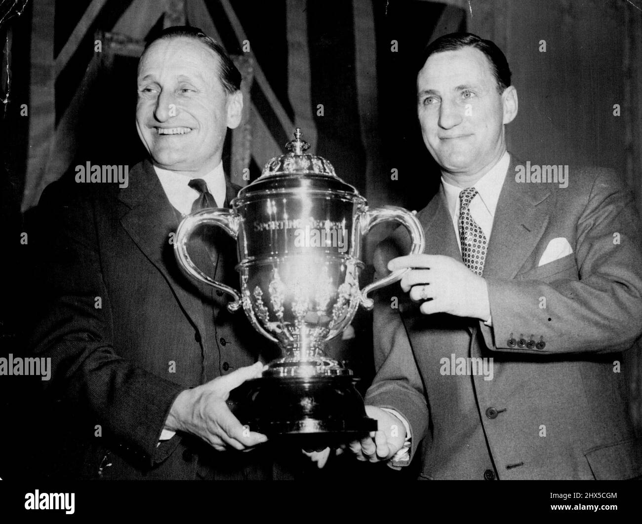 Len Hutton Receives Sportsman Of The Year Trophy -- Man who has batted his way to the top, Len Hutton, of Yorkshire, England's first professional cricket captain, is seen receiving from Lord Broughley left, at London's Savoy Hotel tonight (Monday) the 'Sportsman of the year' trophy awarded to him in the seventh annual national ballet organised by the 'Sporting Record'. Len Hutton is famous as one of the best opening batmen in the world. In the 1952 cricket averages he was shown to have scored 2567 runs in 45 innings. His highest innings score was 189. He made eleven centuries during the season Stock Photo