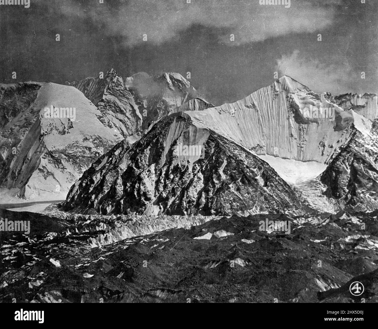 The Mount Everest Expedition: 'The Times' Service -- Scenery of the great Rongbuk Glacier of Mount Everest. Surrounding Everest is one of the finest mountain massifs of the world with huge unnamed peaks and vast winding glaciers. The great sugar loaf of Pumori with hanging glaciers on its almost precipitous slopes has been named by the expedition's surveyors. A fine mountain, but not so high, is the Island peak standing in the centre of the main Roncituk glacier. The peak is beautifully fluted and often avalanches of snow and ice sweep down to the glacier basin below. The glacier in the main v Stock Photo