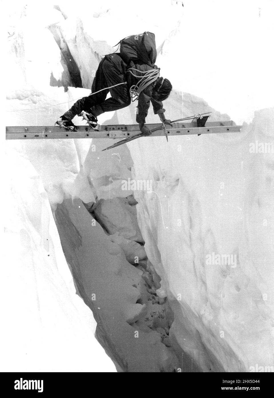 British Everest 1953 Expedition -- A member crossing a crevasse with the aid of one of the special light ladders used by the Expedition..when engaged in marking and improving the route to Camp II. May 21, 1953. Stock Photo