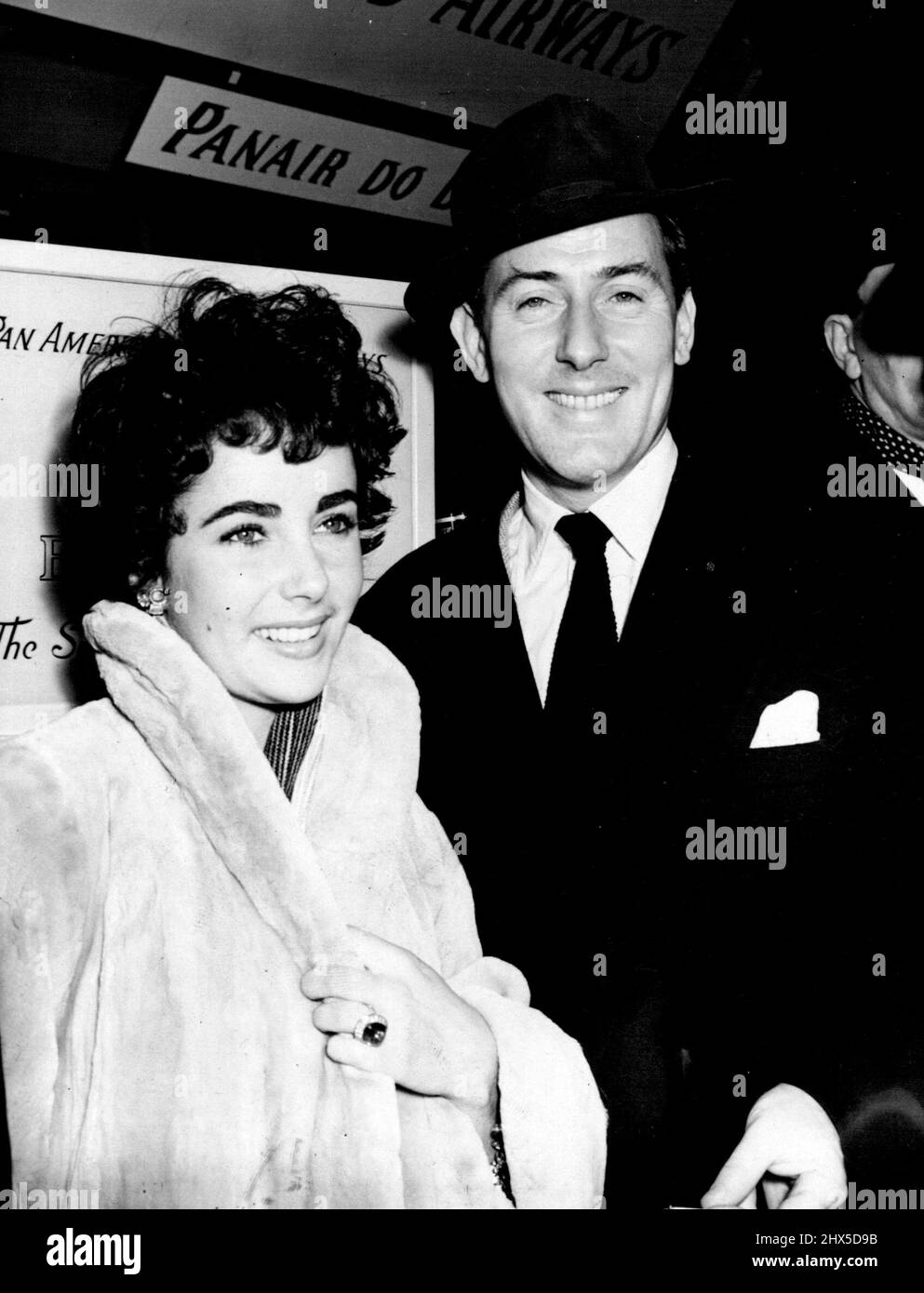 Elizabeth Taylor Here To Wed Michael Wilding, 20 Years Her Senior -- The couple at London airport after Elizabeth Taylor's arrival late last night. Elizabeth is wearing the engagement ring she had to buy herself because Wilding had no dollars. But her has bought her a 'simple English wedding ring', Wilding said last night. It is made of platinum. 19-year-old English film star Elizabeth Taylor, English-born but working in Hollywood, arrived last night at London airport after a two-hour delay through storms. February 20, 1952. (Photo by Paul Popper) Stock Photo