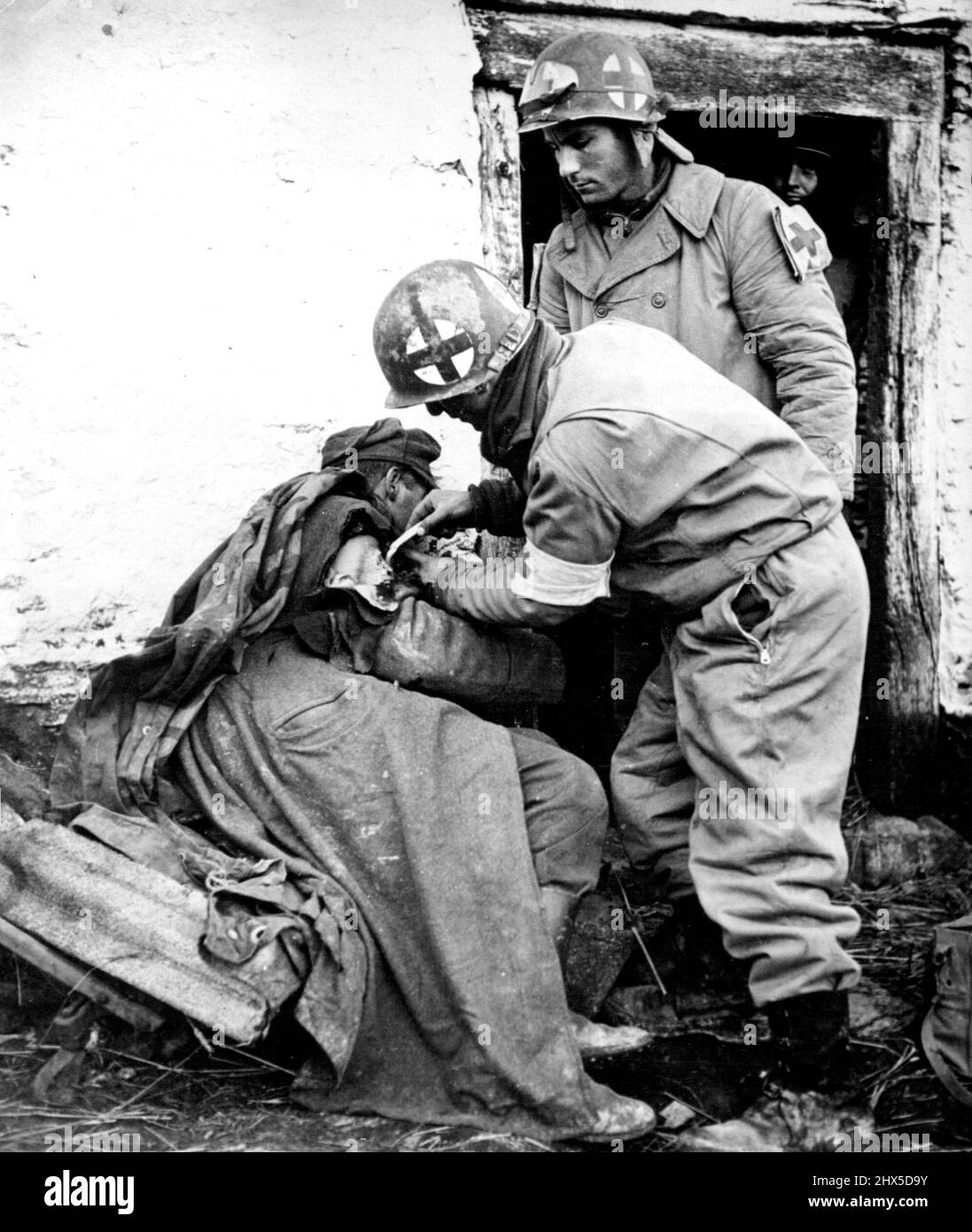 Yanks Treat Wounded German Paratrooper American Medical corpsmen treat a German Paratrooper's shoulder wound during the Yank drive to relieve U.S. Troops trapped in Bastogne by the German December breakthrough into Belgium and Luxembourg. January 6, 1945. (Photo by Associated Press Photo). Stock Photo
