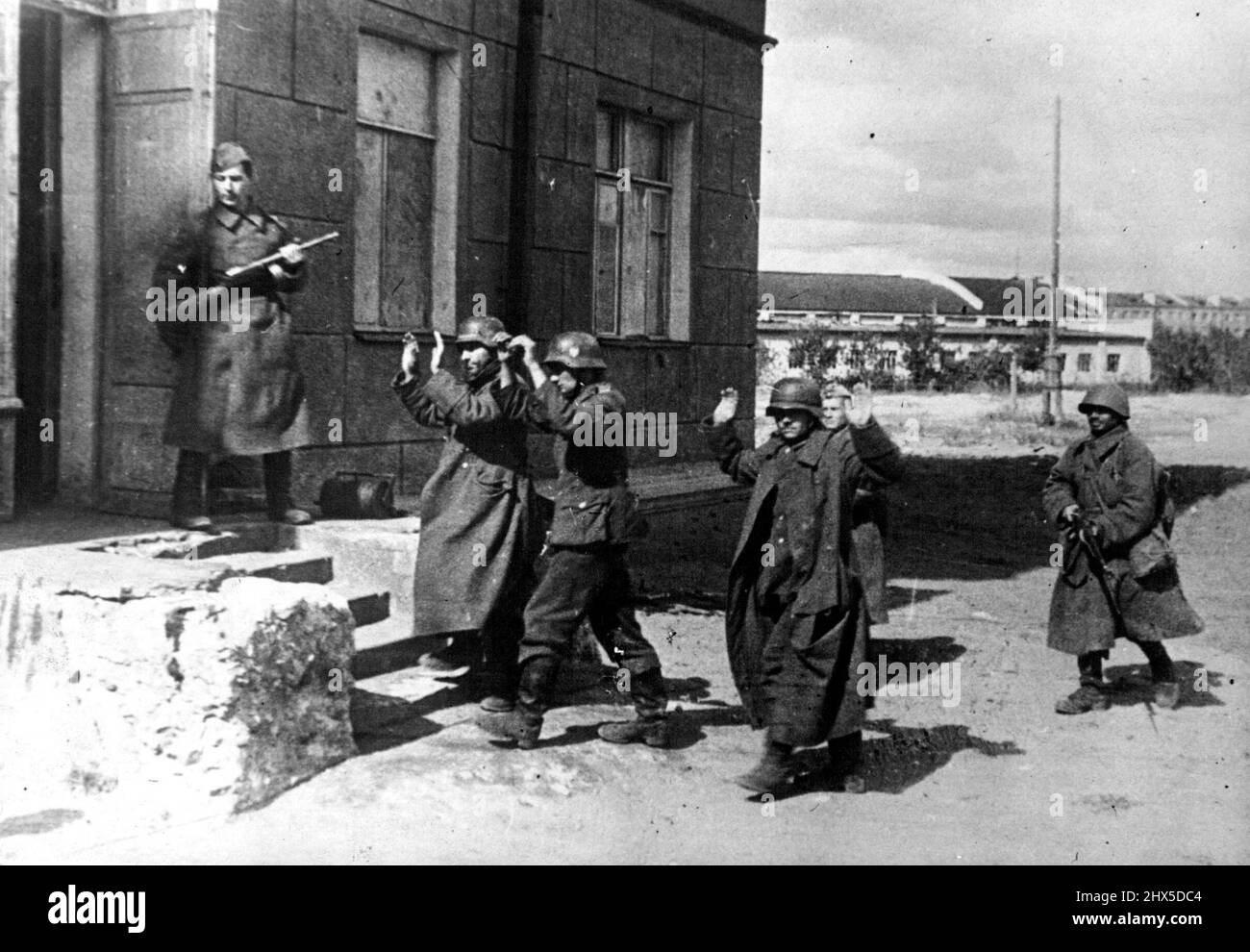 Nazi Prisoners in Russian Hands. Steelhelmeted Nazis, with arms raised in surrender, are marched into staff headquarters for interrogation, at the Voronezh front. March 18, 1944. (Photo by Pictorial Press). Stock Photo