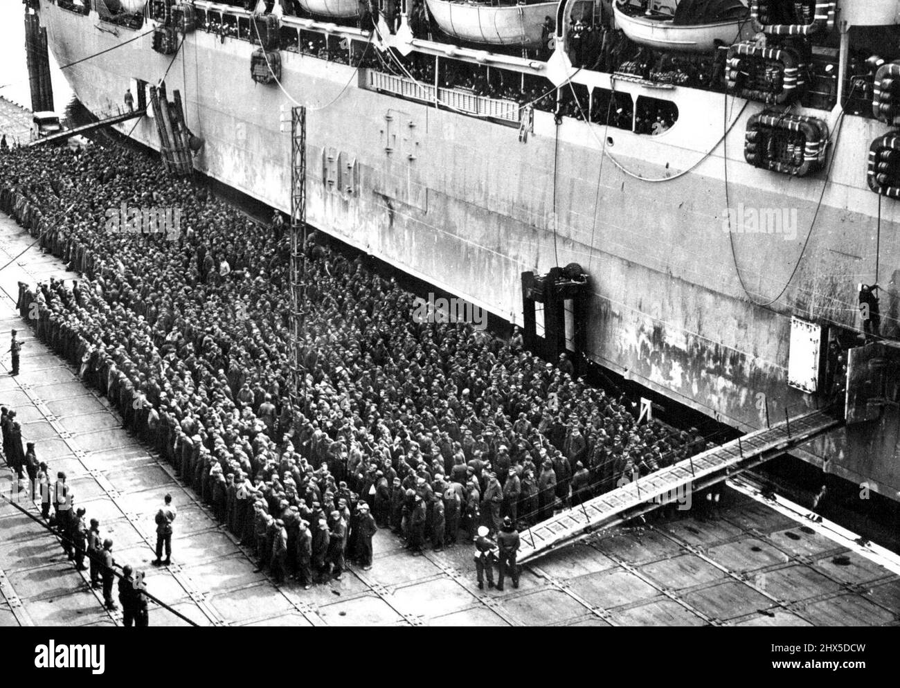 German Prisoners Board Transport for Shipment to U.S. German soldiers stand on the wharves of a French port of embarking waiting to board a troop transport for shipment to prison camps in the U.S. Allied armies in western Europe took 2,472,906 German prisoners between June 6, 1944, the day of the Normandy landings, and April 27, 1945. On April 1, 1945, German prisoners numbering 311,630 were in U.S. camps. The U.S. War Department adheres strickly to the Geneva Convention in its treatment of prisoners of war. June 4, 1945. (Photo by U.S. Office of War Information Picture). Stock Photo