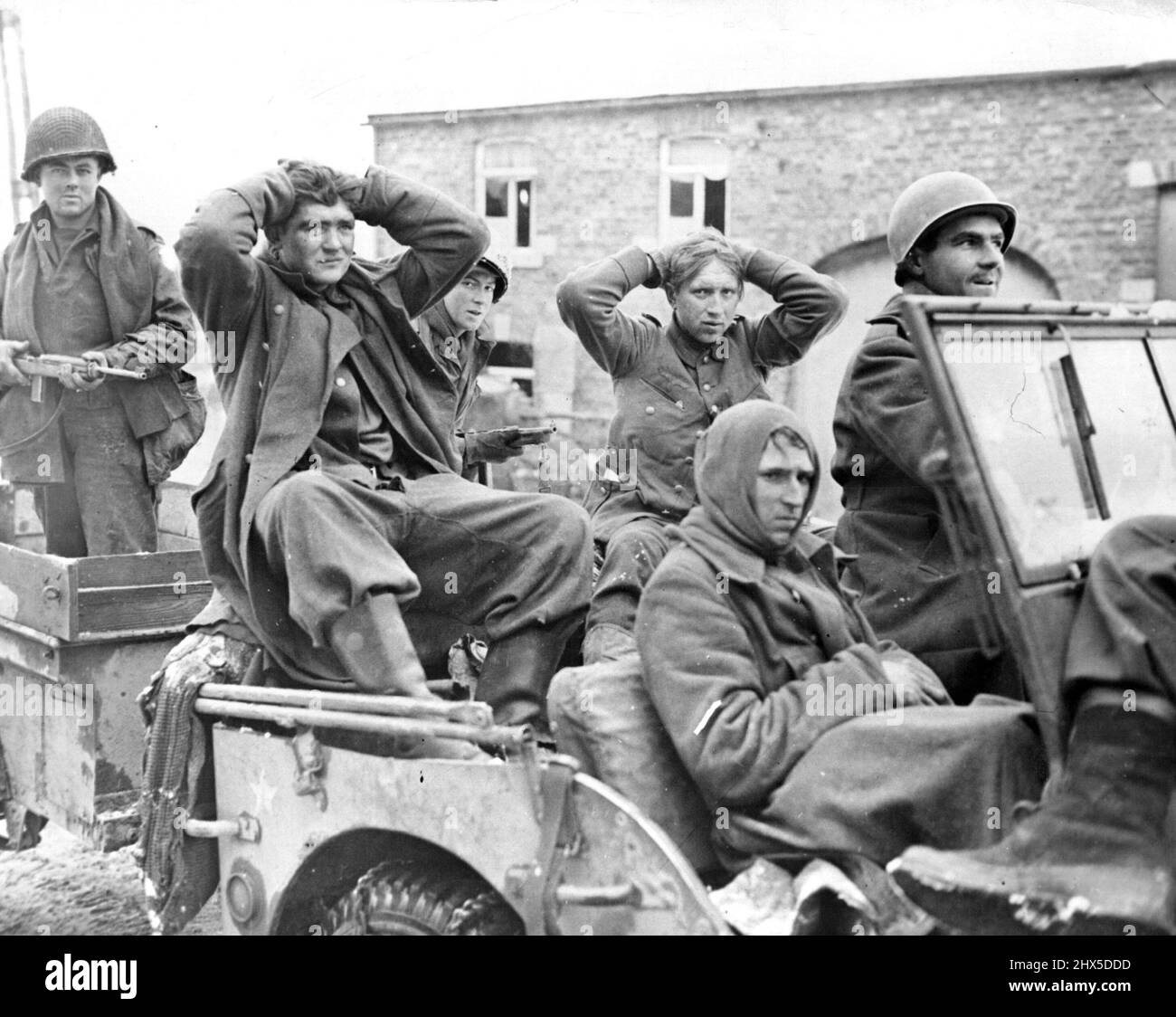 American Soldiers Bring in Nazi Intelligence Patrol U.S. soldiers of the Second Armored Division bring in three Nazis, members of an intelligence patrol, after capturing them on the outskirts of a Belgian town. The two Nazis riding in the roar of the U.S. Army vehicle have their hands on their heads; the prisoner in front has apparently suffered a head injury. Between December 16, 1944, when the enemy launched their counter-offensive on the 'estern Front, and January 3, 1945, it was officially estimated by the Allies that the enemy had suffered 60,000 casualties, including prisoners. At least Stock Photo