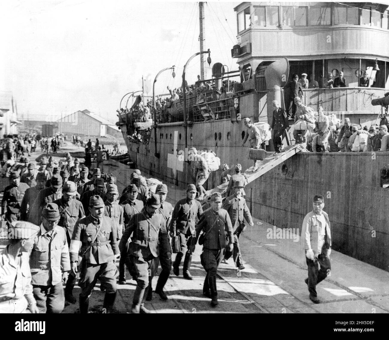 Jap Troops Repatriated from Korea -- Japanese troops are seen here as they debark ship upon return form Korea to Japan for demobilization. The ship 'Kainei Maru' bears white cross as required by Allied powers and is being used to transport troops to Japan and Koreans back to Korea. It is docked at Kyushu port at Fukuoka. October 21, 1945. (Photo by U.S. Army Photo). Stock Photo
