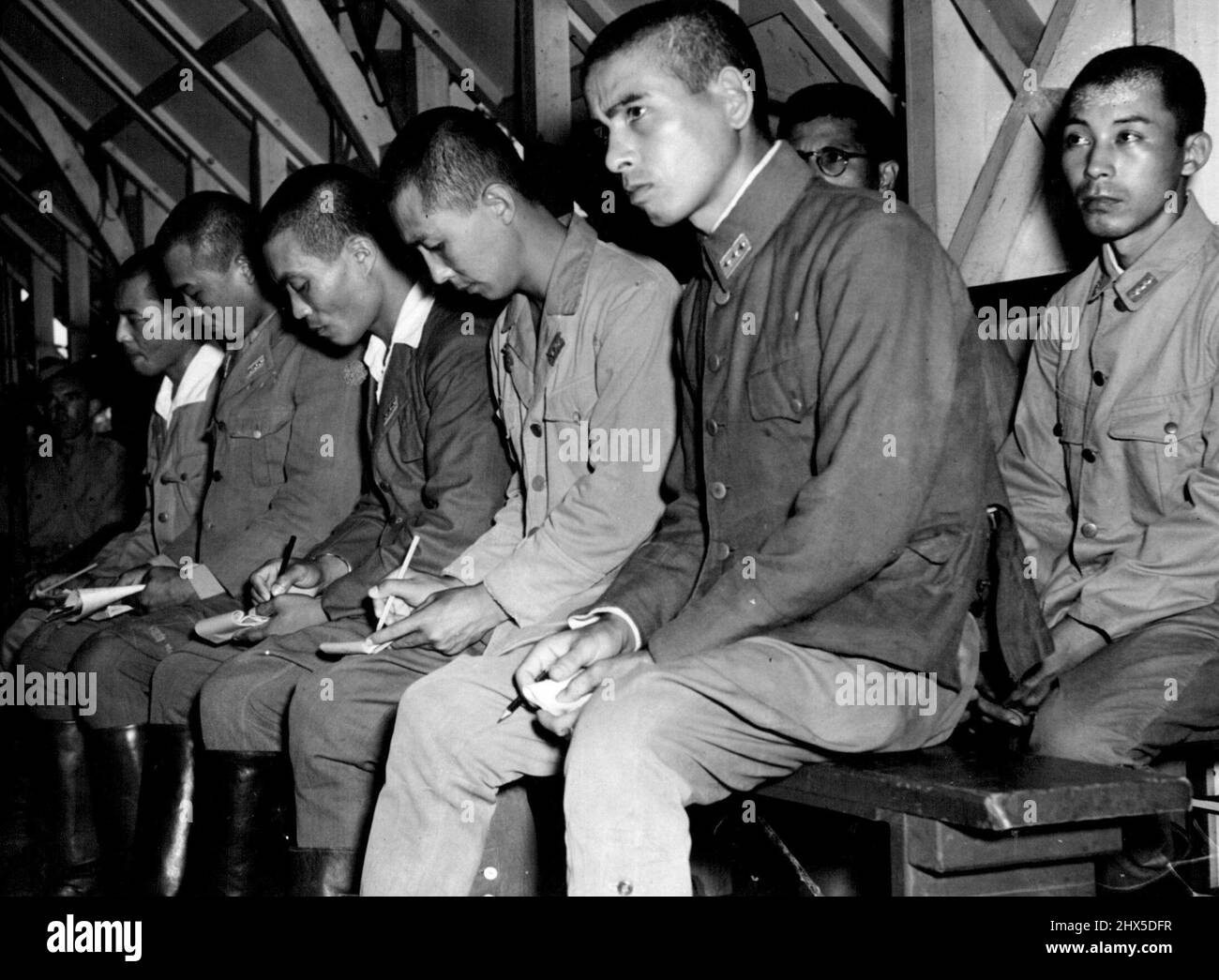 Japanese War Criminals Trials at Darwin. Japanese, on trial in the war crimes court at Darwin, make notes while charges are read. Striking picture of the Japanese on trial at Darwin for atrocities committed on Australians in Timor. They scribble notes as the prosecutor outlines the charges. March 04, 1946. (Photo by Australian Official Photograph). Stock Photo