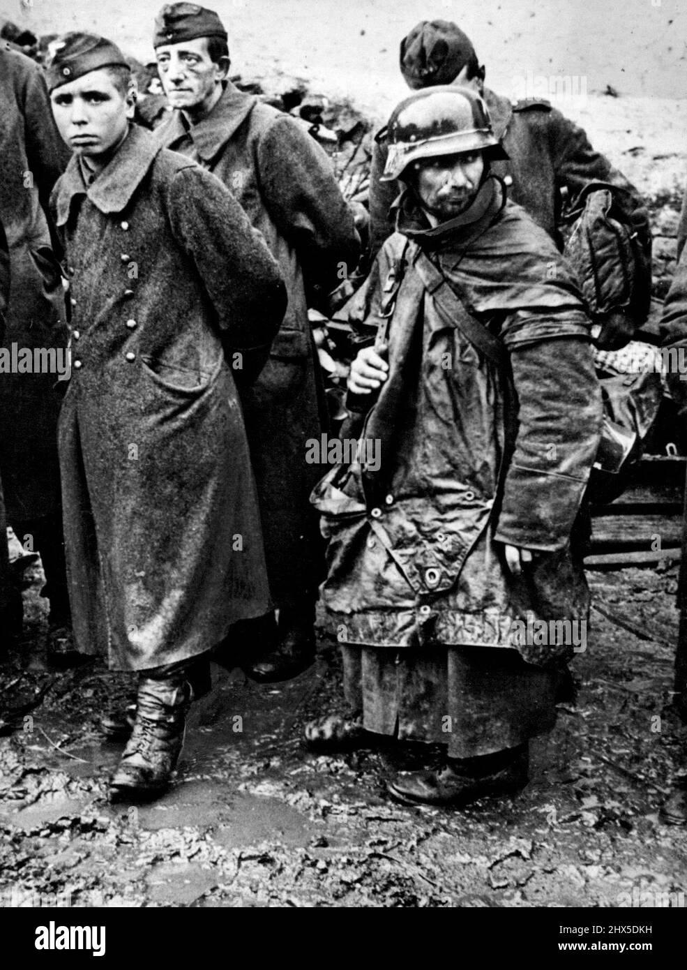 Nazi Driven From Hurtgen Forest : Battle-weary, surrendered Germans stand in the mud of captured Reich soil as they wait near Jungersdorf to be processed for internment. These Naziz were among the last enemy troops to surrender to First U.S. Army soldiers at the close of the battle for the Hurtgen Forest. December 12, 1944, American troops broke through the forest and reached the Roer River in three places, driving to a point within a mile and a quarter of Duren, river bastion on the road to the industrial center of Cologne. January 19, 1945. (Photo by U.S. Office of War Information Picture). Stock Photo