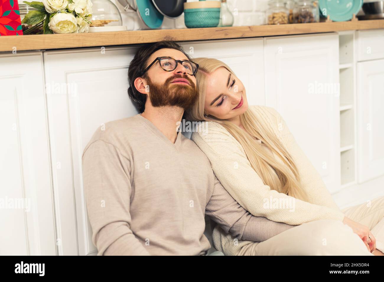 millennial caucasian couple sitting on the kitchen's floor, bonding, cuddling, and contemplating. High quality photo Stock Photo