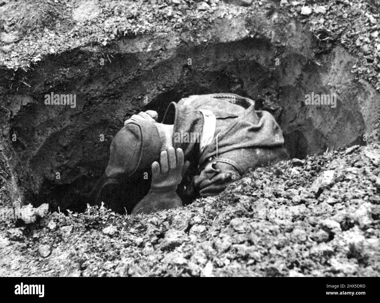 Frightened by the noise of battle, a Nazi covers in his funkhole near Emmerich, and covers his ears while montgomery's heavy guns blast the German positions and Allied armour thunders above him to the receding front. March 31, 1945. (Photo by Gaiger, Planet) Stock Photo