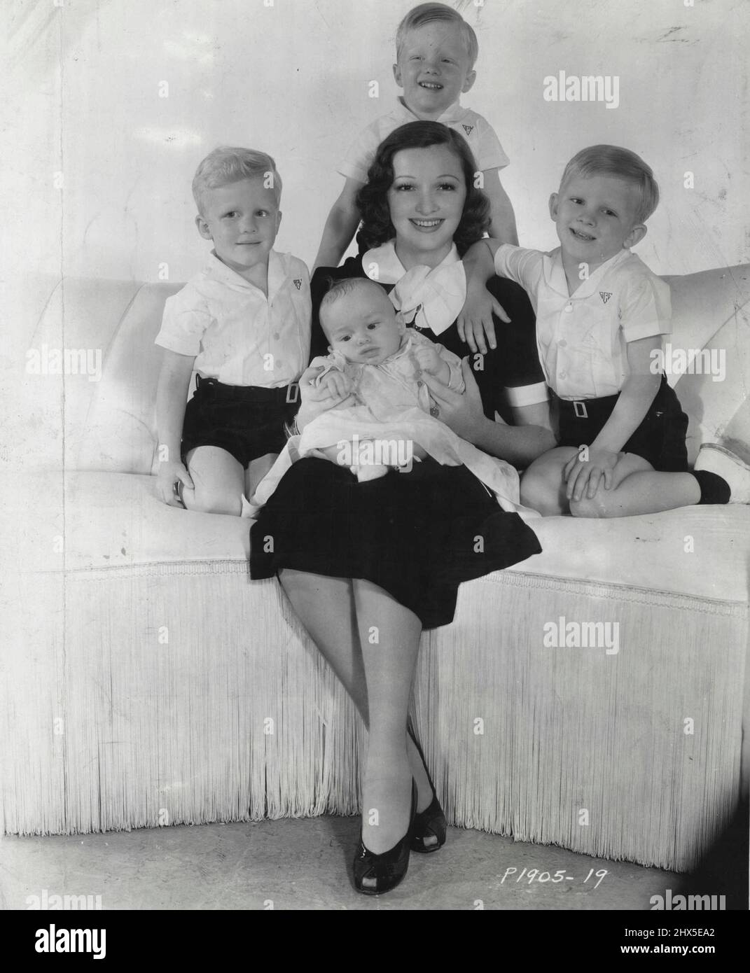 Why Bing Croons -- Five reasons why Bing Crosby Sings so much are in this photograph of this wife, beautiful Dixie Lee, and their four children. Left to right, the older boys are Phillip and Dennis, the twins, and Gary. Baby Lindsay is sitting on this Mother's Lap. Gary made his screen debut as an extra in a mob scene in Paramount's 'sing You Sinners' Star ***** in which his father stars. January 13, 1940. Stock Photo