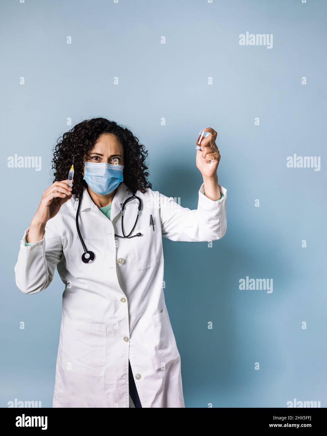 hispanic woman doctor with wavy hair holding vaccine injection for pandemic in Mexico latin America Stock Photo