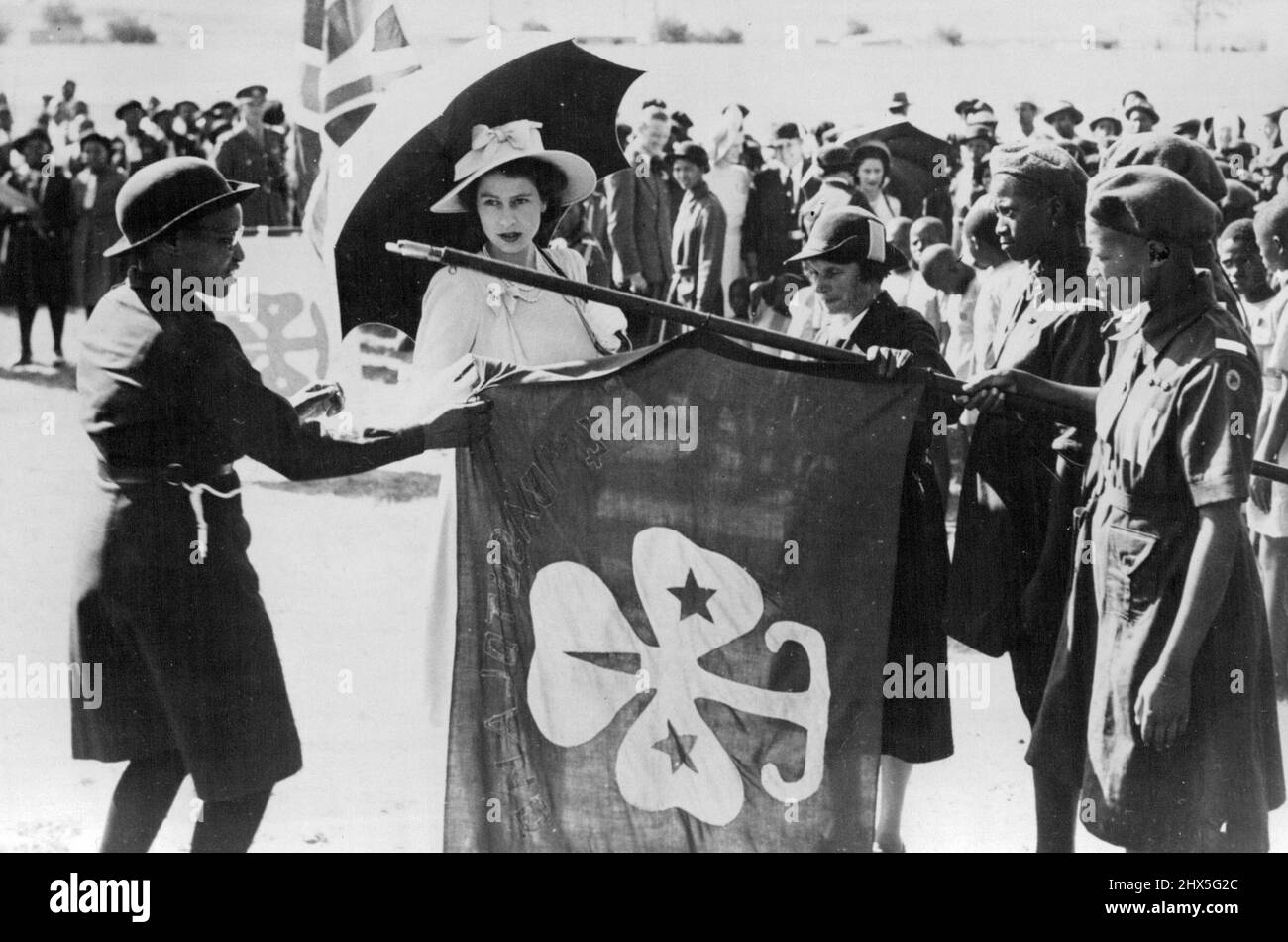 Over 70,000 Basuto Greet Royal Family -- H.R.H. Princess Elizabeth examines a banner at a Parade of native Girl Guides held at Maseru in honor of the Royal Visit. Between 70,000 and 90,000 Basuto assembled in and around Maseru to welcome the Royal family, Many of the natives had trekked for more than a week, camping by the wayside, in order to be in capital to pay homage to their king. March 17, 1947. Stock Photo