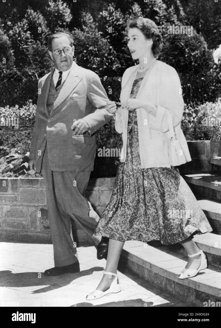 The New Queen In Africa - Before Tragic News Of Father's Death -- Princess Elizabeth, now Queen following the sudden, tragic death of her father, King George VI, walks through the Kenya sunshine with Sir Philip Mitchell, Governor of Kenya, at Sagana lodge, Nyeri, the Colony's wedding present to the Princess and her husband, the Duke of Edinburgh. (This picture of the Royal tour was received in London just a few hours after the announcement of the King's death). February 02, 1952. Stock Photo