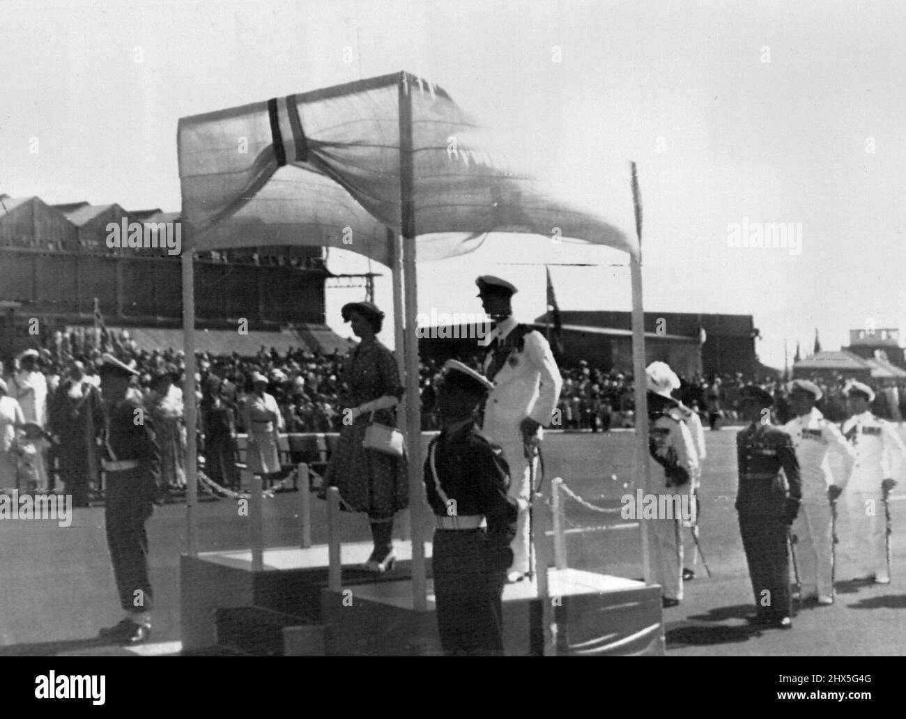 Princes And Duke Arrive In Nairobi -- Princess Elizabeth and the Duke of Edinburgh, wearing a white uniform, stand to attention during the National Anthem on their arrival at Eastleigh airport, Nairobi. Their Argonaut aircraft landed exactly on Schedule. They were met by the Governor of Kenya, Sir Philip Mitchell, and representatives of the Army, Navy and Air force. The Royal Couple are to be the guests of Sir Philip and Lady Mitchell during their stay in Nairobi. February 01, 1952. Stock Photo