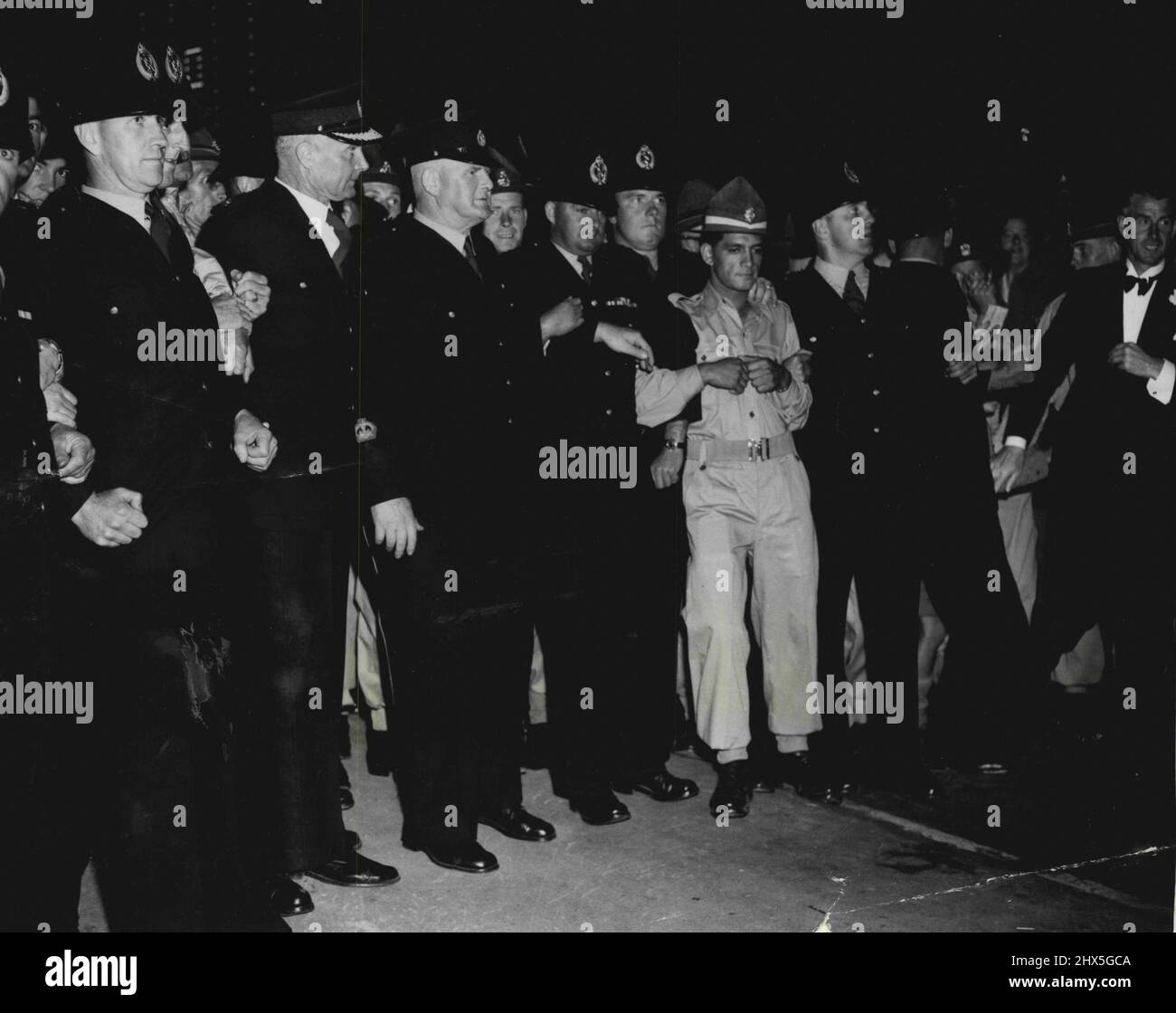 Police keep back the crowds as Queen Elizabeth arrives at her hotel after the civic dinner at Palmerston North, New Zealand. January 12, 1954. Stock Photo