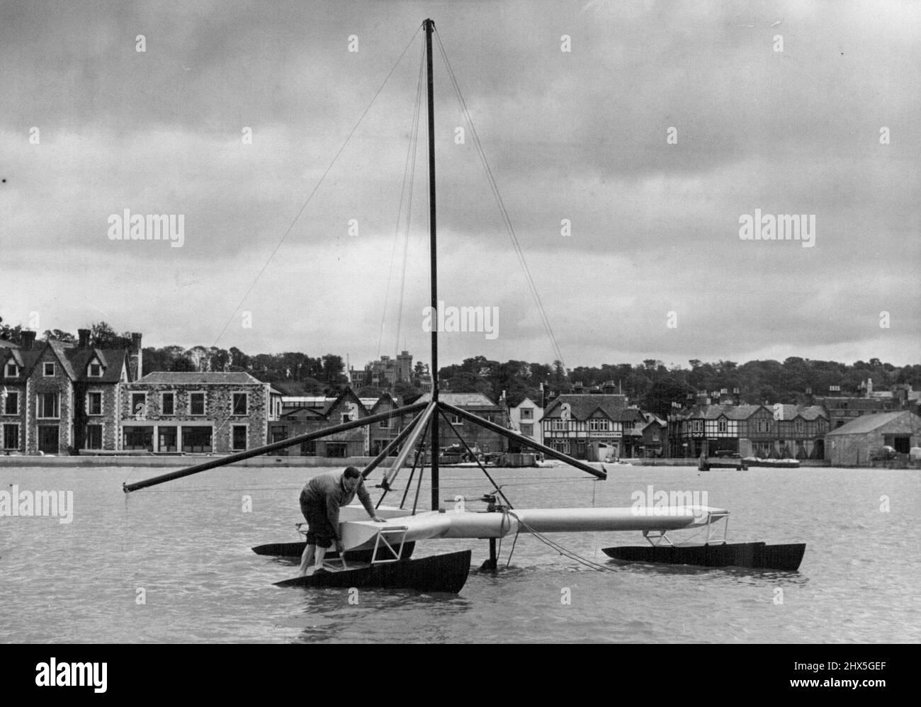 'Helicopter' Yacht Begins Trials At Cowes -- Mr. H.M. Barkla, designer of the Triscaph 'Trion' seen making adjustments to one of the vessel's floats at her moorings off Cowes, where she is now undergoing trials. Almost ready for launching at the Cowes (Isle of Wight) Corinthian Yacht Club is the Triscaph yacht 'Trion', a revolutionary-designed vessel, which resembles a floating helicopter. It is the design of Mr. H.M. Barkla, a physicist at St. Andrews University and an enthusiastic yachtsman, who is a member of the Royal Tay Yacht Club and the Cambridge Cruising Club. July 30, 1954. (Photo by Stock Photo