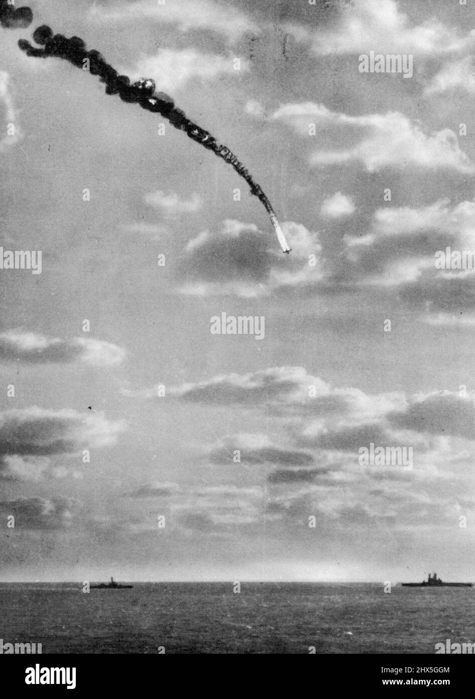 Flaming Jap Plane Plunges in Pacific set ablaze by anti-aircraft fire from a U.S. Essex class carrier, this Jap Bomber leaves a trail of smoke and flame as it plungs toward the Pacific off Kyushu. An Iowa class battleship (right) and a destroyer, part of a U.S. Task Force, are at bottom. May 14, 1945. (Photo by Associated Press Photo). Stock Photo