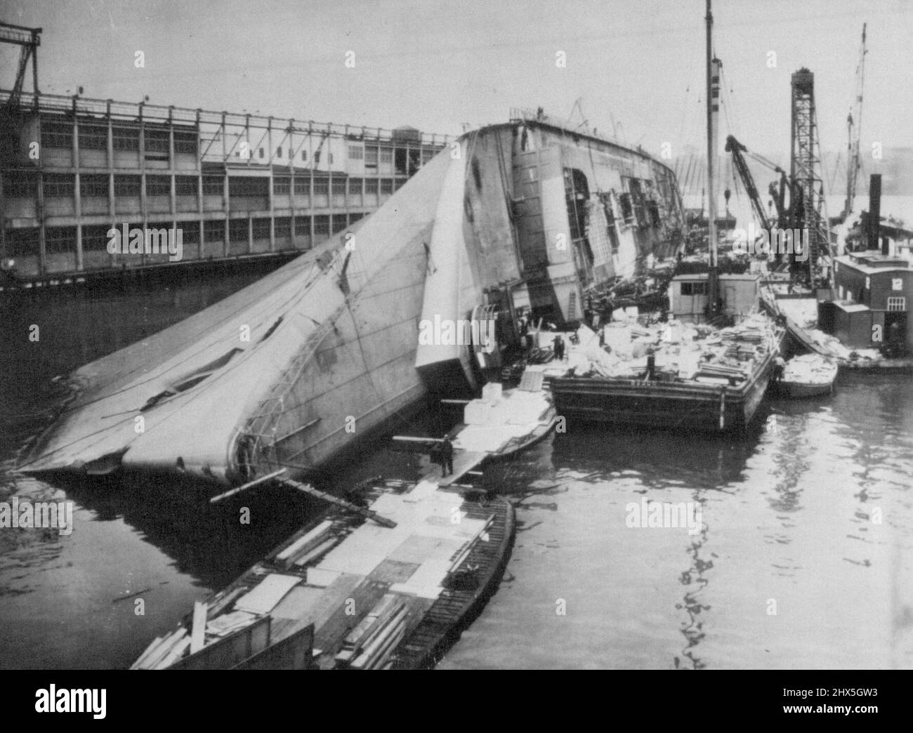 Navy To Refloat The Capsized Normandie -- Preliminary work in raising the burned and capsized liner Normandie at its pier is under way. The Navy announced today the job would take about a year. Barges and other equipment lie alongside the overturned giant in this picture made yesterday. May 21, 1942. (Photo by AP Wirephoto). More infor During World War II, Normandie was seized by U.S. authorities at New York and renamed USS Lafayette. In 1942, the liner caught fire while being converted to a troopship, capsized onto her port side and came to rest on the mud of the Hudson River at Pier 88 Stock Photo