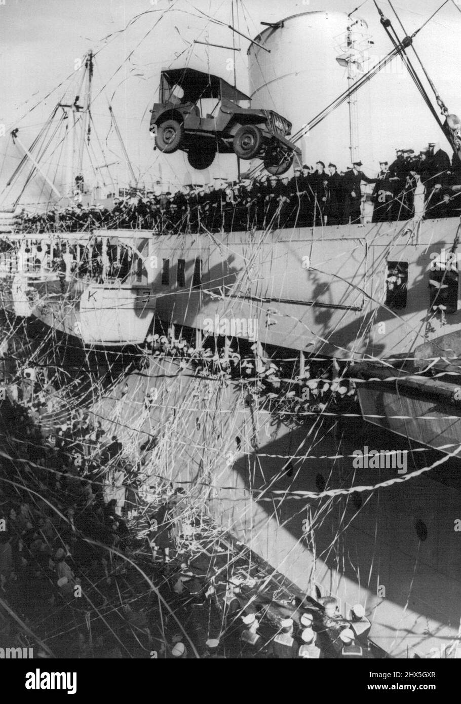 Swinging High above the wharf this jeep breaks farewell streamers at Port Melbourne today. It was being loaded on board the Kanimbla which is taking Naval and Air Force men to England to collect Australia's first aircraft carrier HMAS Sydney. June 29, 1948. Stock Photo